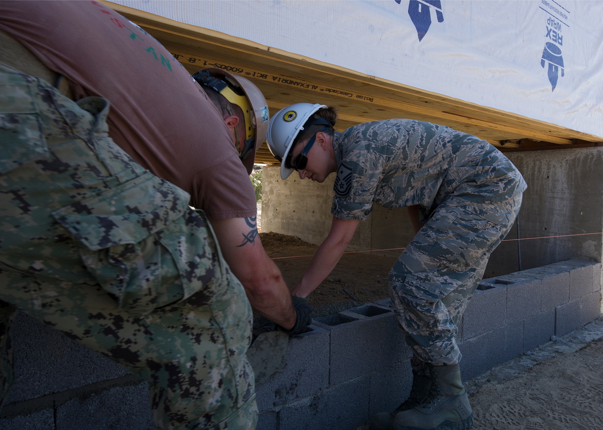 Builder 1st Class Carl Phillips, Naval Mobile Construction Battalion 22, teaches Master Sgt. Elizabeth Clark, 446th Civil Engineer Squadron 1st sergeant, how to set bricks for the foundation of a newly constructed house in Gallup, NM, June 13, 2016. Airmen and Navy Seabee’s participated in Operation Footprint, a partnership of the Southwest Indian Foundation and the Department of Defense’s Innovative Readiness Training program which provides an avenue for training military members .The two-week joint service training allowed members to construct homes which will be given to tribal members of the Navajo Nation who are in need. (U.S. Air Force Reserve photo by Tech. Sgt. Bryan Hull)