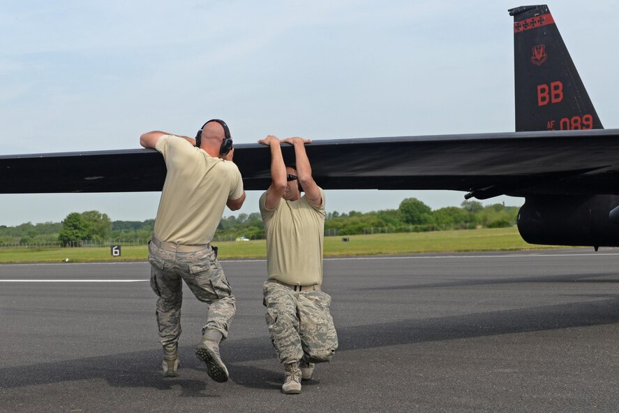 9th Aircraft Maintenance Squadron Airmen pull down a U-2 Dragon Lady's wing to level the aircraft June 7, 2016, at Royal Air Force Fairford, Gloucestershire, England. Due to the bicycle-style landing gear, the U-2 tips to one side when it comes to a complete stop. The use of temporary-supporting wheels are placed under the wings when it's not in flight. (U.S. Air Force photo by Senior Airman Ramon A. Adelan)