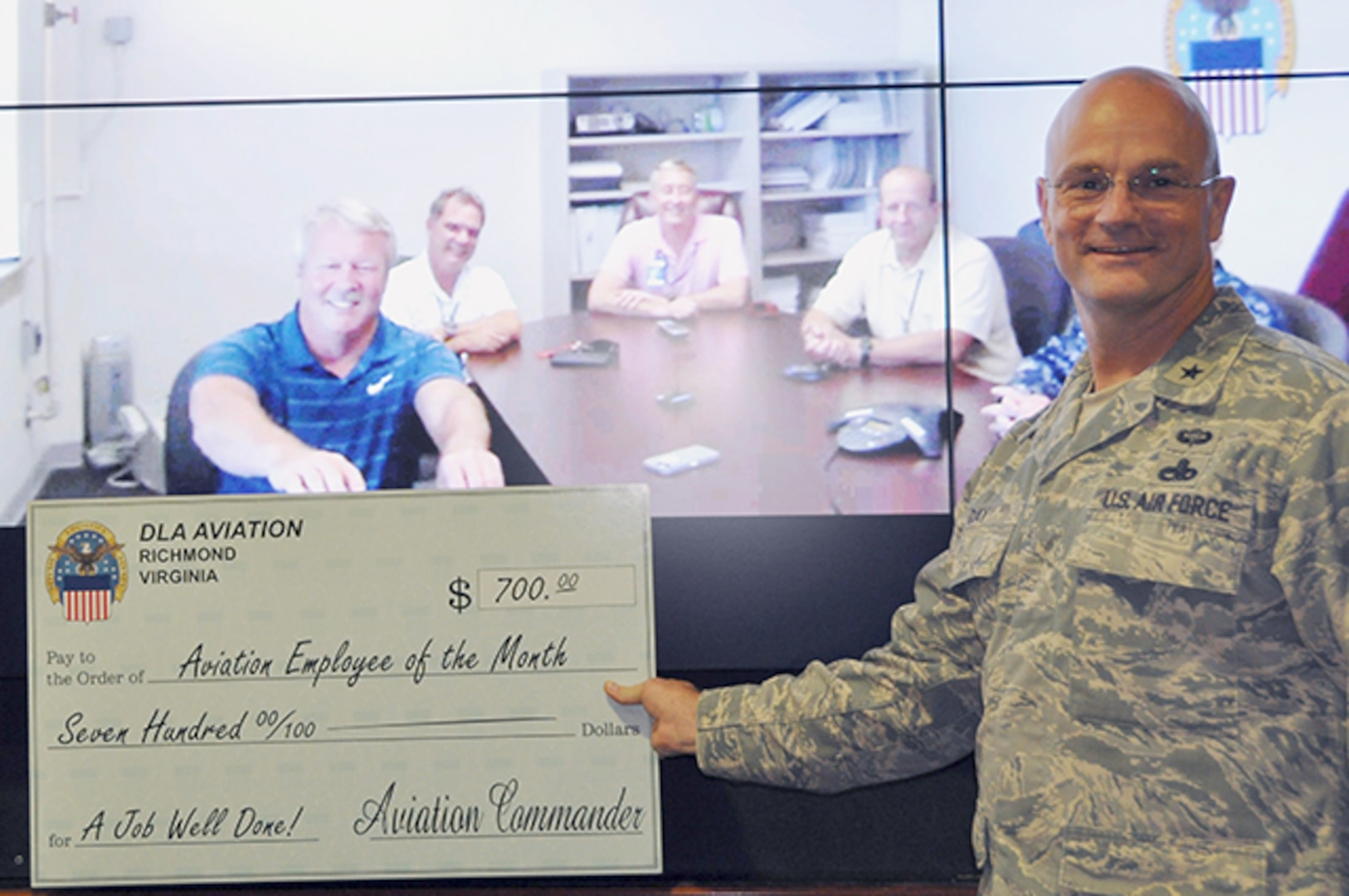 Richard McGrory, a materiel planner with Defense Logistics Agency Aviation at Jacksonville, Florida, receives a check from Defense Logistics Agency Aviation Commander Air Force Brig. Gen. Allan Day in recognition of being named the April Employee of the Month during a June 8, 2016 video ceremony. 