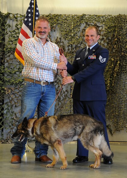Staff Sgt. Sean King, 319th Security Forces Squadron military working dog handler, passes the leash to Chad Sherod, 319th Logistics Readiness Squadron munitions inspector, as part of an official MWD retirement ceremony June 14, 2016, on Grand Forks Air Force Base, N.D. Sherod and his family adopted Ferra, 319th SFS military working dog, after her nearly ten years of service. (U.S. Air Force photo by Senior Airman Ryan Sparks/Released)
