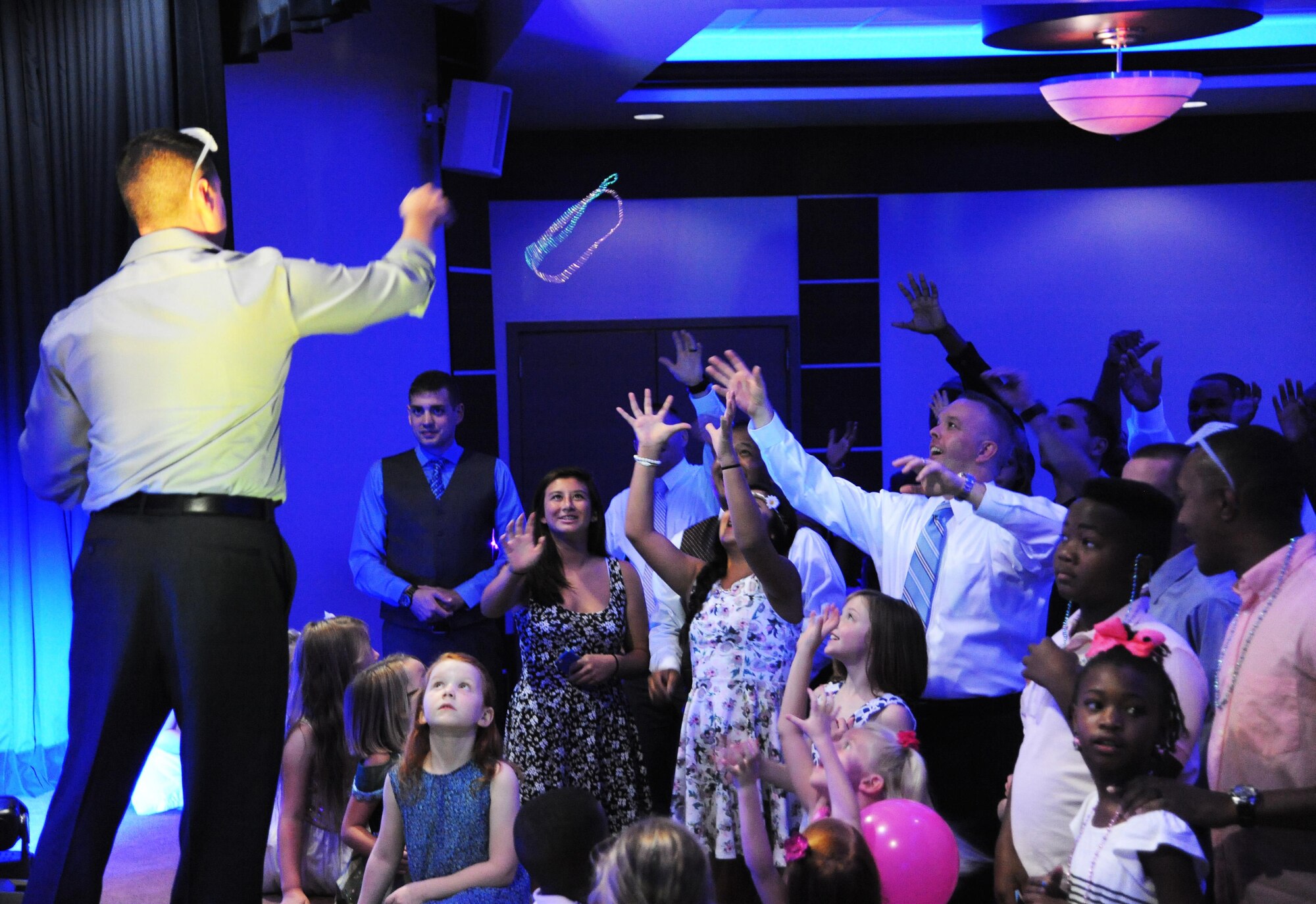 Staff Sgt. Frank Rivas, NCO in charge of resources and readiness with the 6th Air Mobility Wing chaplain corps, throws a beaded necklace to a trivia contest winner during the Daddy/Child dance on MacDill Air Force Base, Fla., June 11, 2016. Fathers from throughout MacDill brought their children to dance to enjoy games, food, music and dancing. (U.S. Air Force photo by Airman Adam R. Shanks)