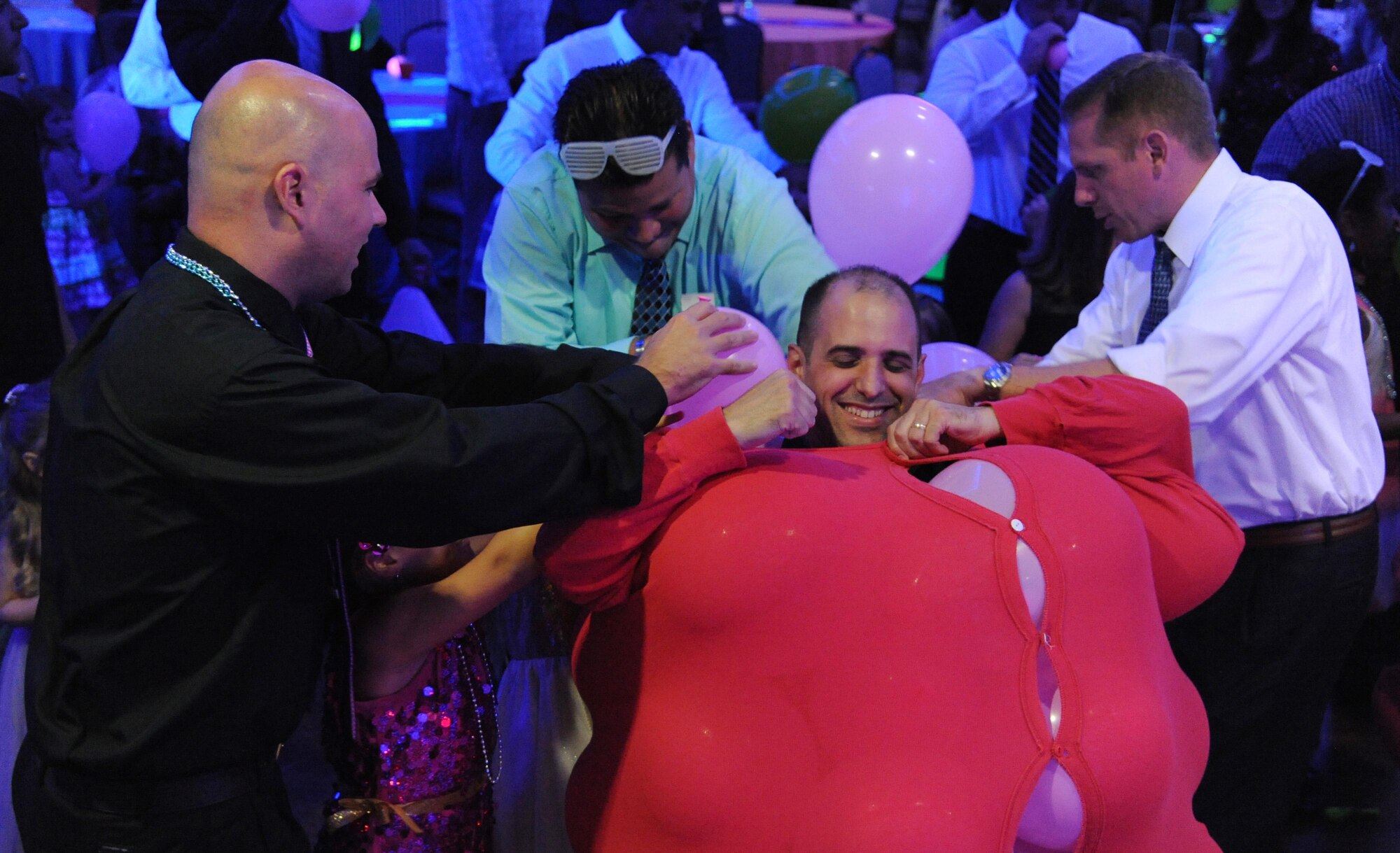 Fathers stuff balloons into a suit worn by a contestant before a dance competition during the Daddy/Child dance June 11, 2016, at MacDill Air Force Base, Fla. Three teams led by fathers competed to see who could dance the best while wearing the balloon-filled suits. (U.S. Air Force photo by Airman Adam R. Shanks)