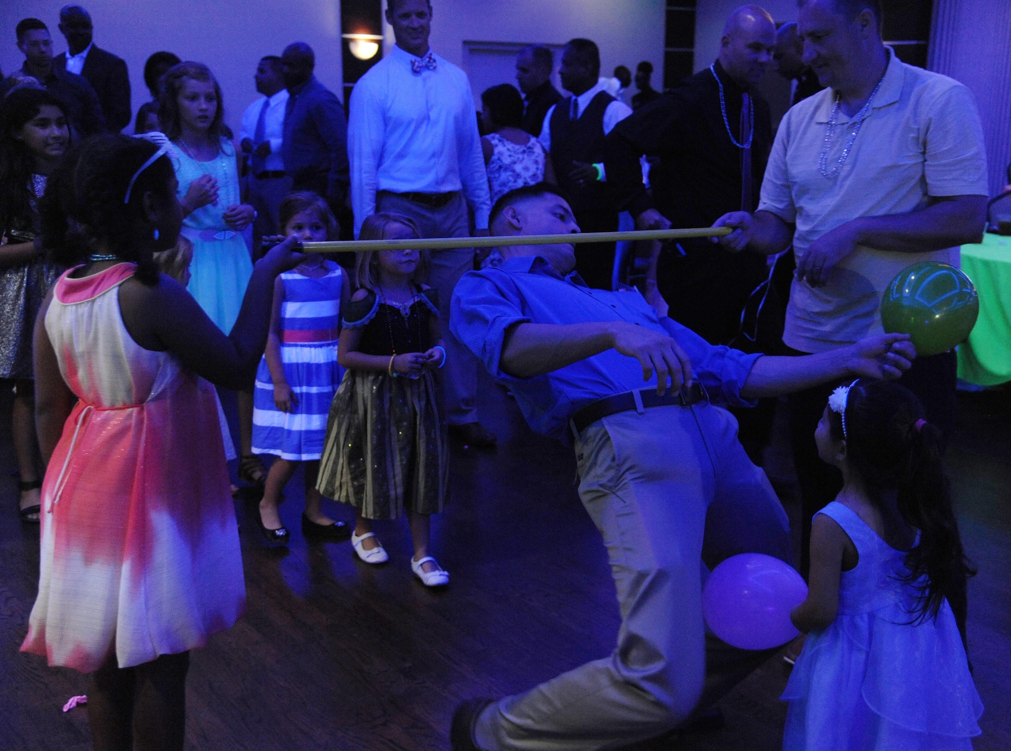 A father competes in a limbo competition during the Daddy/Child dance on MacDill Air Force Base, Fla., June 11, 2016. Fathers and their children from around MacDill joined together for food, games and music. (U.S. Air Force photo by Airman Adam R. Shanks)
