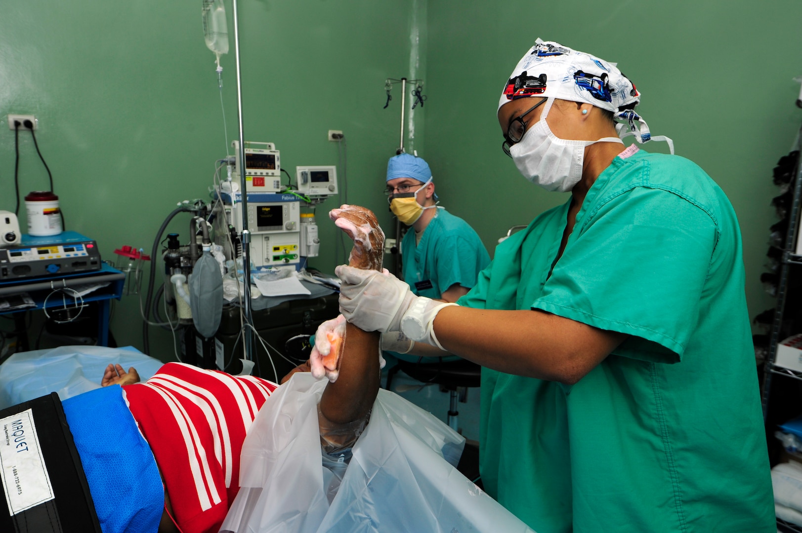 Capt. Lauren Quirao, 506th Expeditionary Medical Operations operating room nurse, cleans Espinal Ledi’s arm in preparation for a bi-lateral carpal tunnel release surgery June 8, at Rio San Juan hospital, Dominican Republic.  Quirao is part of the tenth and final Medical Readiness Training Exercise or MEDRETE rotation during Exercise NEW HORIZONS 2016. Quirao is deployed from the 59th Medical Wing, Joint Base San Antonio, Texas. (U.S. Air Force photo by Master Sgt. Chenzira Mallory/released)