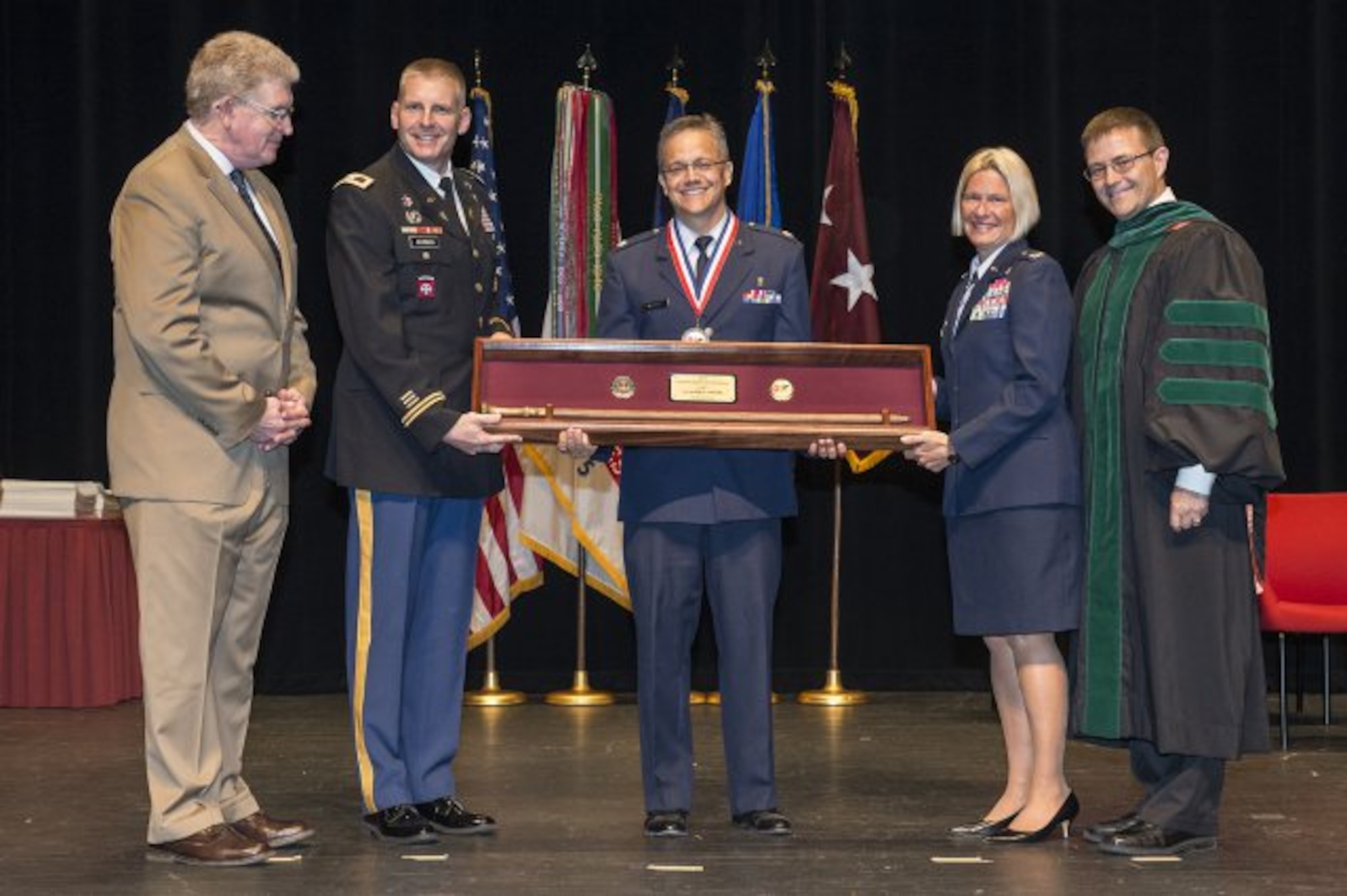 Air Force Lt. Col. Erik Weitzel is presented the Gold Headed Cane by retired Lt. Gen. Eric Schoomaker, BAMC Commander Col. Jeffrey Johnson, Col. Rachel Lefebvre, and Dr. Woodson "Scott" Jones, dean, San Antonio Uniformed Services Health Education Consortium, during the SAUSHEC awards and graduation ceremony in downtown San Antonio, June 10, 2016. (U.S. Air Force photo/Senior Airman Krystal Wright)