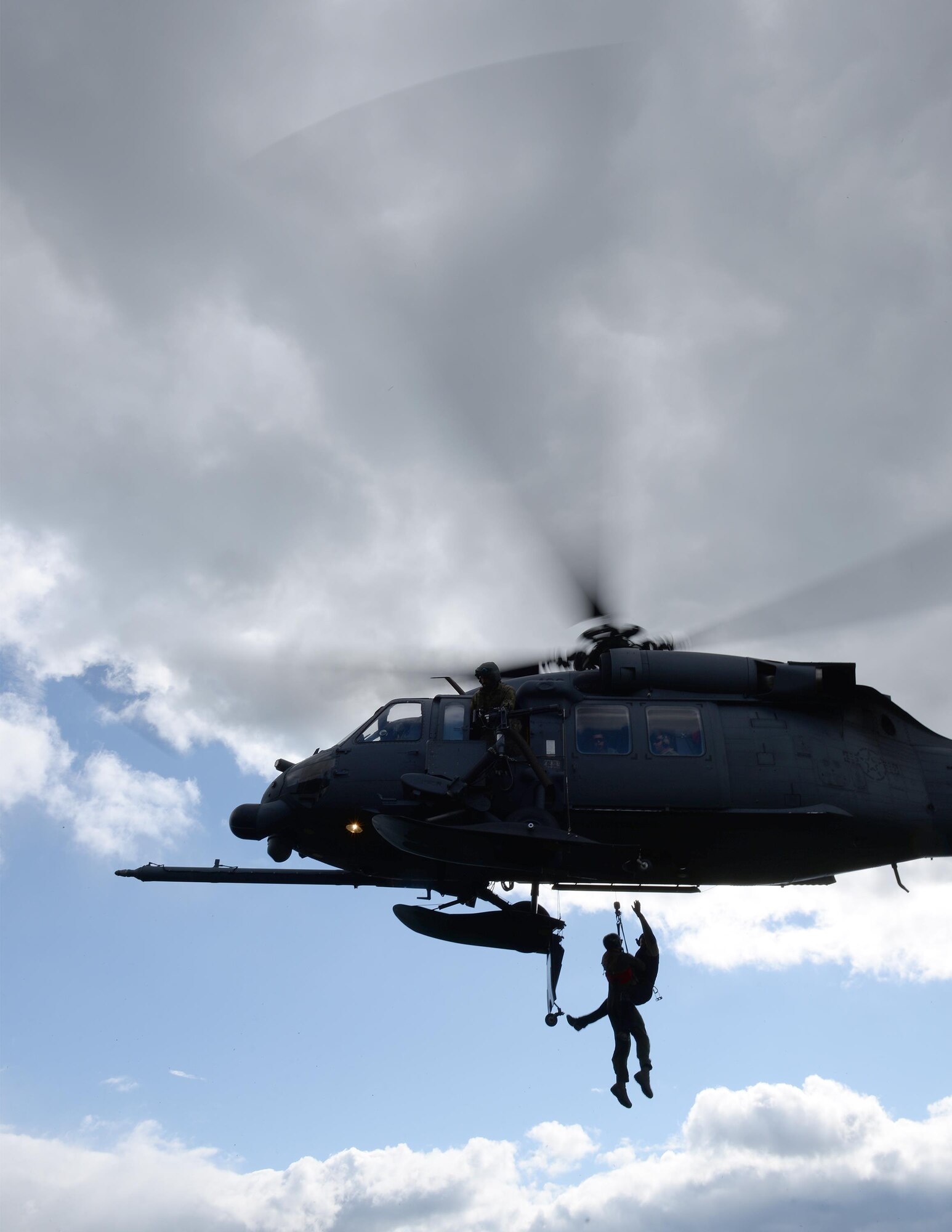 A U.S. Air Force flight engineer gunner assigned to the Alaska Air National Guard's 210th Rescue Squadron (RQS) Detachment (Det) 1 watches for opposing forces as a pararescuman hoists an extracted pilot into an HH-60G Pave Hawk rescue helicopter at a training site inside the Joint Pacific Alaska Range Complex as part of a personnel recovery exercise June 14, 2016, during RED FLAG-Alaska (RF-A) 16-2. The 210th RQS Det 1, based at Eielson Air Force Base, Alaska, regularly trains for rescue missions, providing a crucial mission during RF-A exercises, which occur in a more than 67,000 square mile area known as the Joint Pacific Alaska Range Complex. (U.S. Air Force photo by Master Sgt. Karen J. Tomasik)