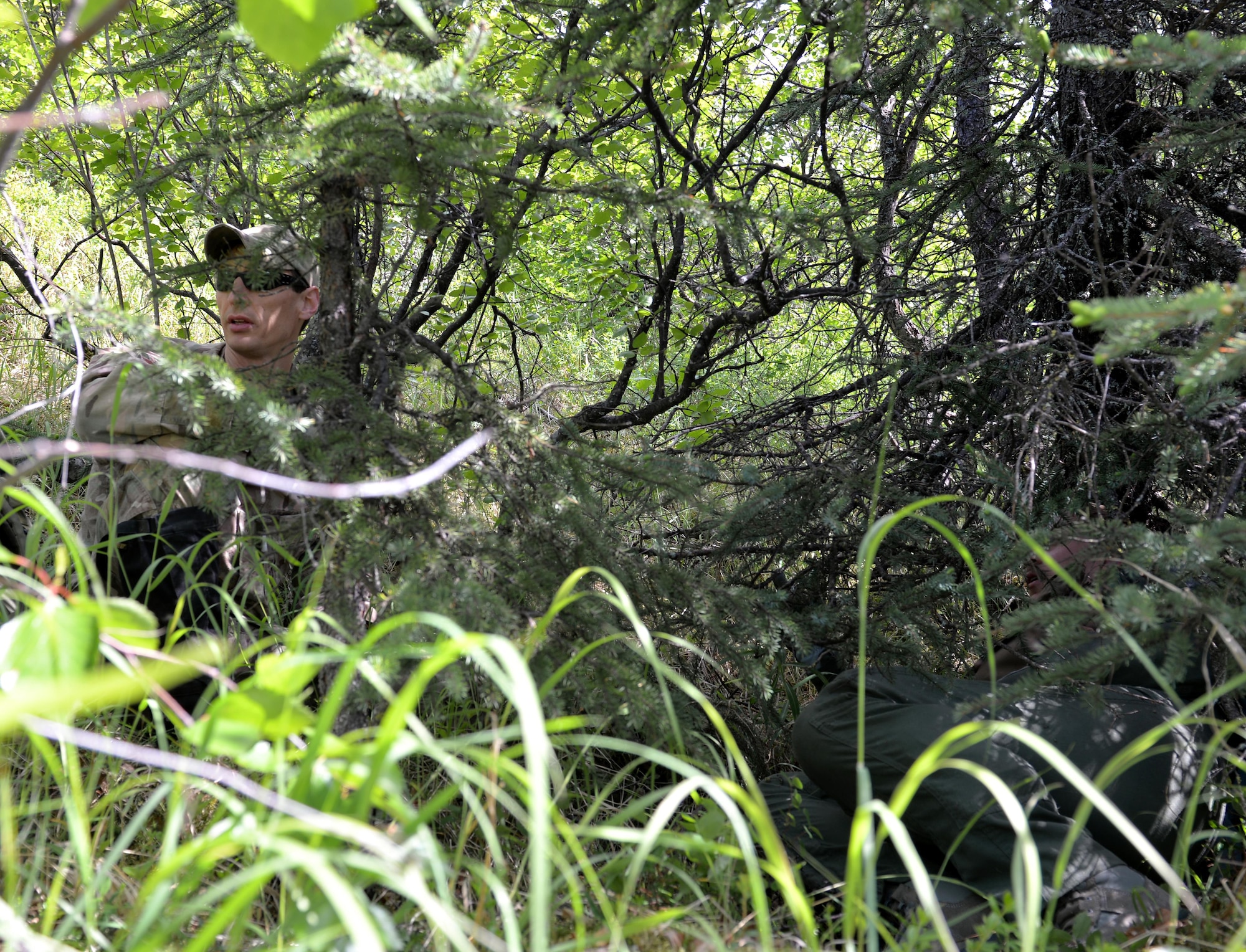 U.S. Air Force Master Sgt. Kurtis Douge, a survival, evasion, resistance and escape craftsman assigned as the 353rd Combat Training Squadron personnel recovery division superintendent, talks about evasion steps with Capt. Keli Kaaekuahiwi, an A-10 pilot assigned to the 354th Fighter Squadron out of Davis-Monthan Air Force Base, Ariz., as they use the terrain to conceal their location during a personnel recovery exercise at a training site in the Joint Pacific Alaska Range Complex, June 14, 2016, during RED FLAG-Alaska (RF-A) 16-2. RF-A is a series of Pacific Air Forces commander-directed field training exercises for U.S. and partner nation forces, enabling joint and international units like the Bulldogs to sharpen their combat skills in a realistic threat environment inside the Joint Pacific Alaska Range Complex, the largest instrumented air, ground and electronic combat training range in the world. (U.S. Air Force photo by Master Sgt. Karen J. Tomasik/Released)