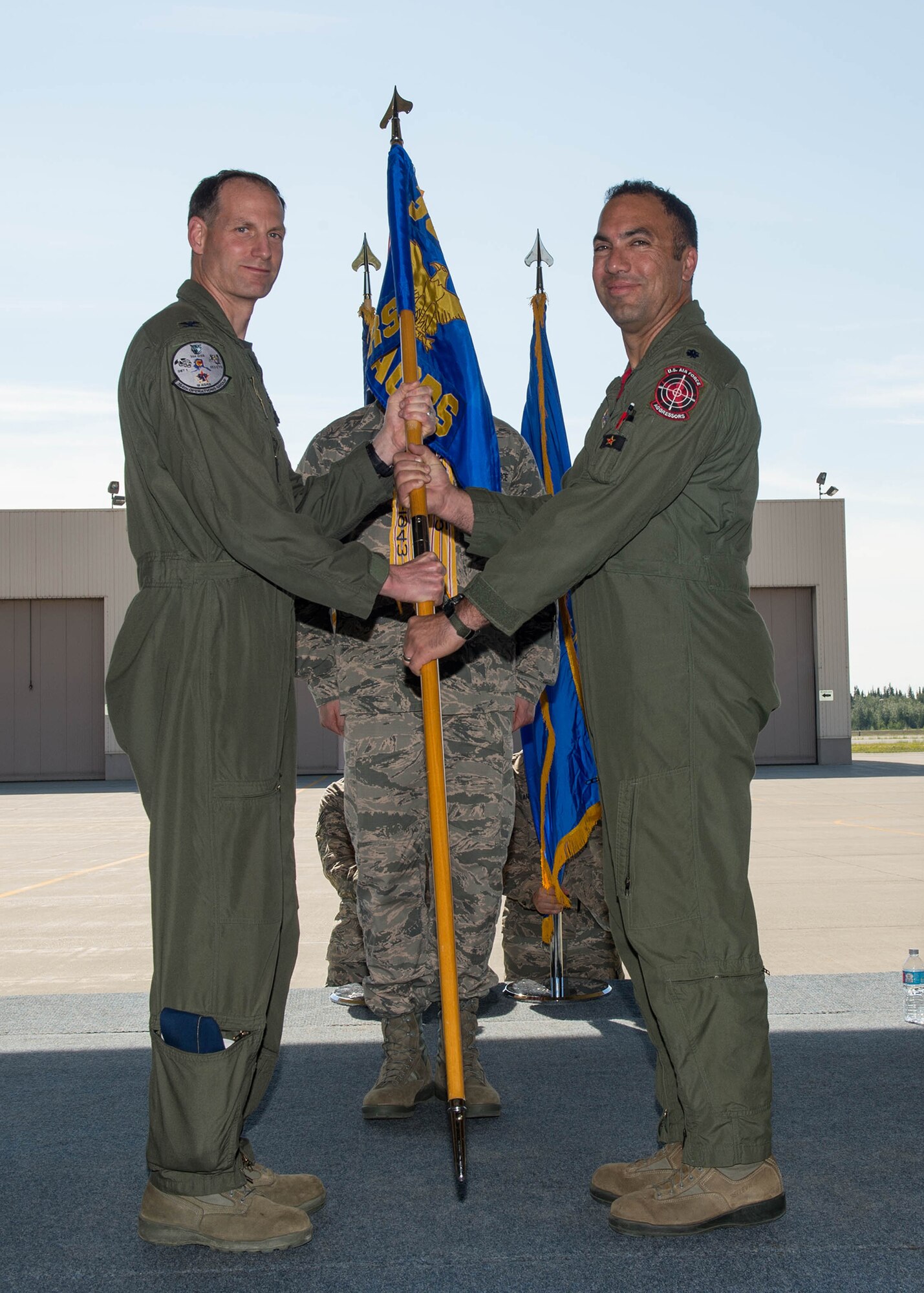 U.S. Air Force Col. Brian Toth, the 354th Operations Group commander, passes the 18th Aggressor Squadron guidon to Lt. Col. Julio Rodriguez, the new 18th AGRS commander, in a change of command ceremony, June 17, 2016, at Eielson Air Force Base, Alaska. Lt. Col. David Graham, the outgoing group commander, will move on to Aviano Air Base, Italy. (U.S. Air Force photo by Staff Sgt. Shawn Nickel/Released)