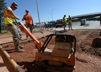 Senior Airman Matthew Farnworth, 28th Civil Engineer Squadron equipment technician, operates a plate tamper during construction of a new sidewalk in front of the Holbrook Library at Ellsworth Air Force Base, S.D., June 16, 2016. The renovation project, consisting of new paved sidewalks and a new patio, is scheduled to be completed by the end of June. (U.S. Air Force photo by Senior Airman Anania Tekurio/Released)