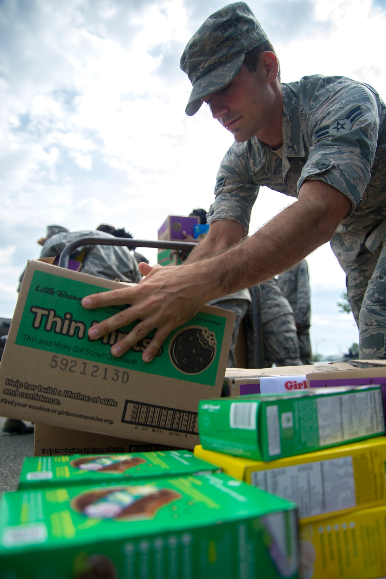Airman 1st Class Philip Bryant, 11th Wing Public Affairs photojournalist, assists with distribution of Girl Scout Cookies on Joint Base Andrews, Md., June 15, 2016. Volunteers from the six wings on JBA helped with the breakdown and delivery of approximately 5,000 boxes of cookies. (U.S. Air Force photo by Airman Gabrielle Spalding)
