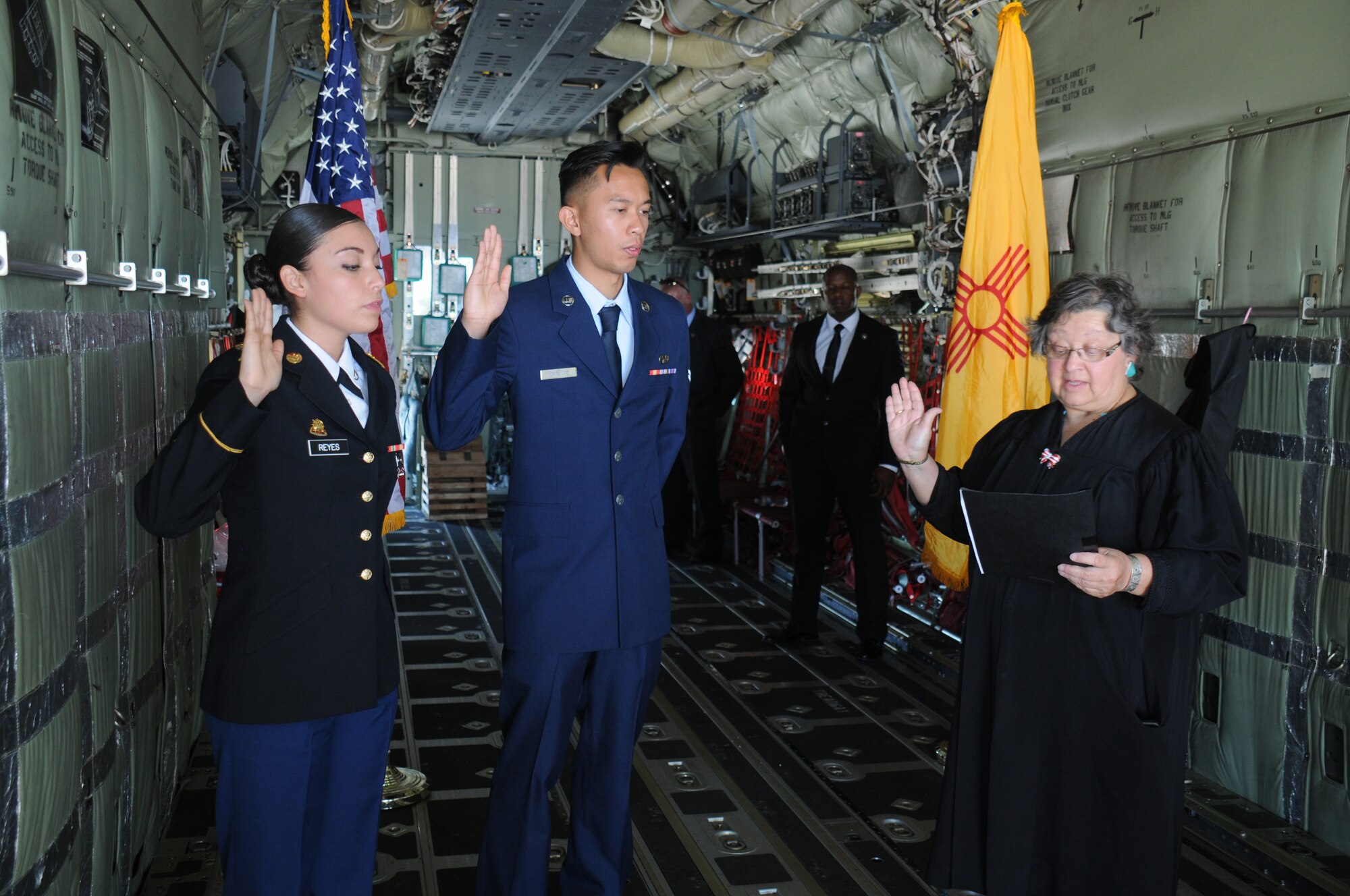 Private 1st Class Diana Guadalupe Reyes Manriquez, of the New Mexico National Guard's 1116th Transportation Company, and Airman 1st Class Aaron Matulac, of the 27th Special Operations Wing at Cannon Air Force Base, take the oath of U.S. citizenship as administered by U.S. Magistrate Judge Christina Armijo on an aircraft at the Kirtland Air Force Base 75th anniversary air show June 4. (Photo by Dennis Carlson)