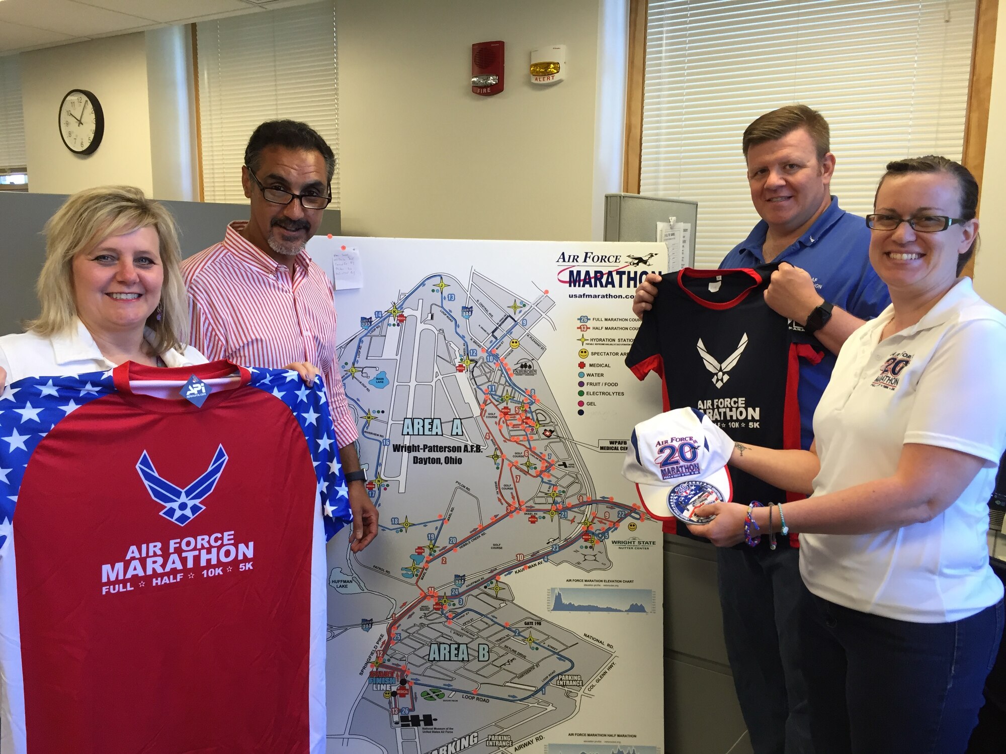 Left to right: Air Force Marathon staff members Jeanette Monaghan, volunteer coordinator; Rob Aguiar, director; Rick Perron, marketing coordinator; and Rachael McKinney, office administrator, display some of the shirts, hat and patch associated with the 20th running of the Air Force Marathon on Sept. 17 at Wright-Patterson Air Force Base. (Skywrighter photo/Amy Rollins)