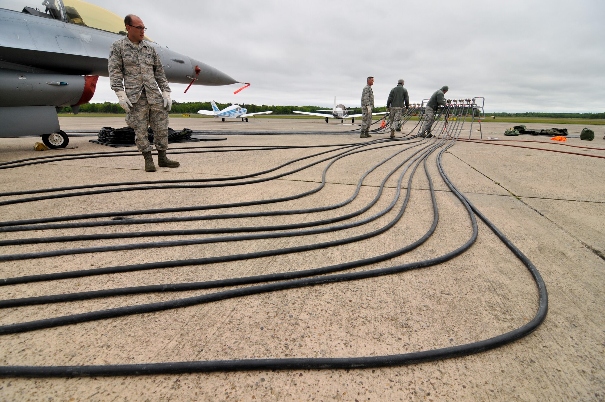 A picture of U.S. Air Force Staff Sgt. Matt Wagner, aircraft maintainer with the New Jersey Air National Guard's 177th Fighter Wing, surveying pneumatic hoses connected to a lifting bag assembly under a decommissioned F-16D Fighting Falcon.