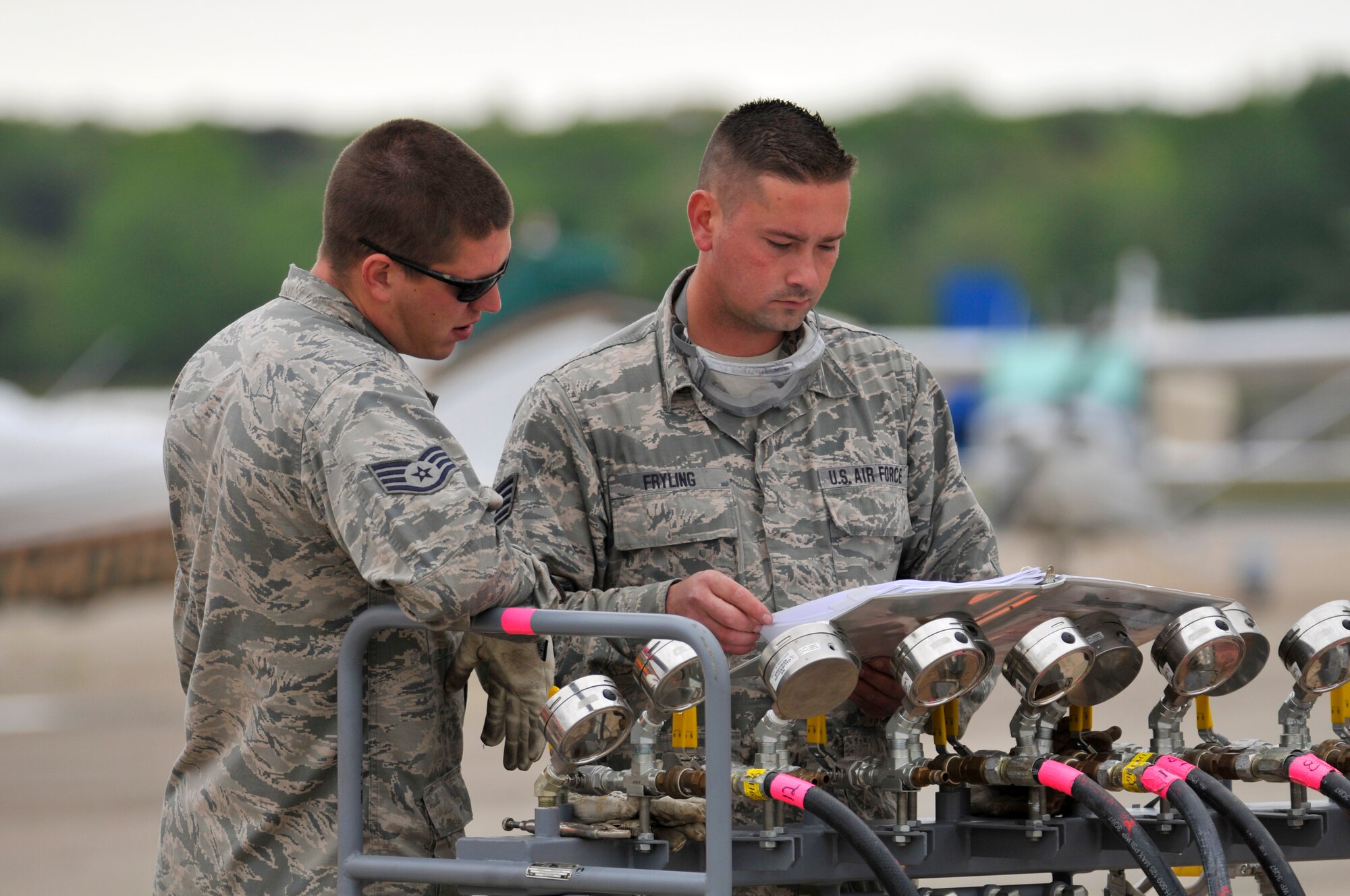 A picture of U.S. Air Force Staff Sgts. Edward Fryling and James Dzierwinski reviewing a training guide on manifold pressure operations of a pneumatic a lifting bag assembly.