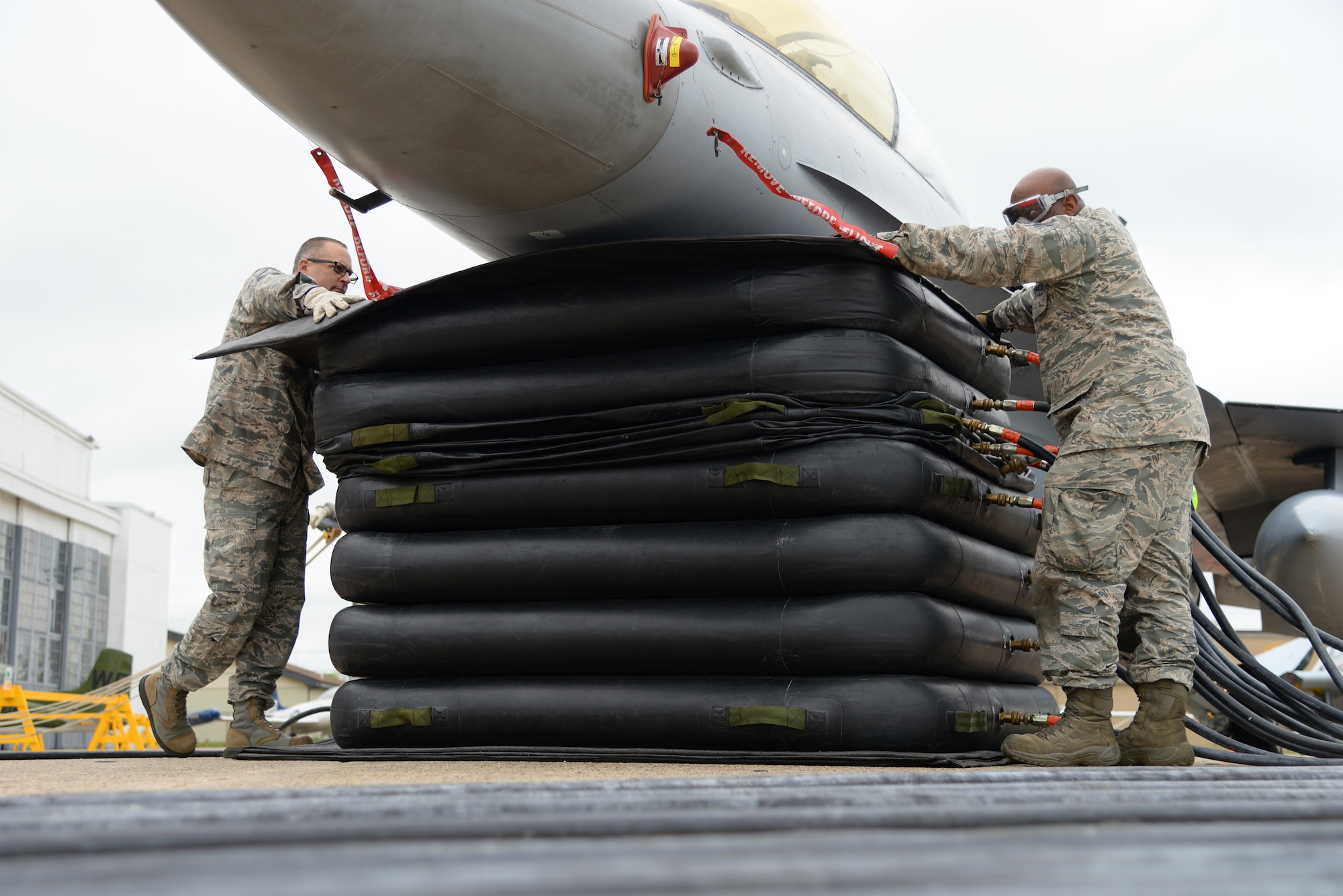 A picture of U.S. Air Force Master Sgt. Gerard Sheehan and Staff Sgt. Corey McPherson monitoring inflation of a pneumatic lifting bag assembly.