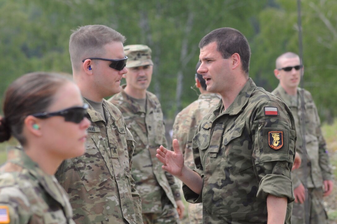 Polish Army Pfc. Mircim Jasek, a translator, with 1st Warsaw Armored Brigade in Warsaw, Poland, translates instructions to U.S. Army Sgt. Joseph Pischieri, a medic with the 30th Medical Brigade, located in Wiesbaden, Germany during a marksmanship competition with Polish Army Soldiers, using Polish weapons at the Warszawska Brygada Pancerna Range in Warsaw, Poland, May 28.