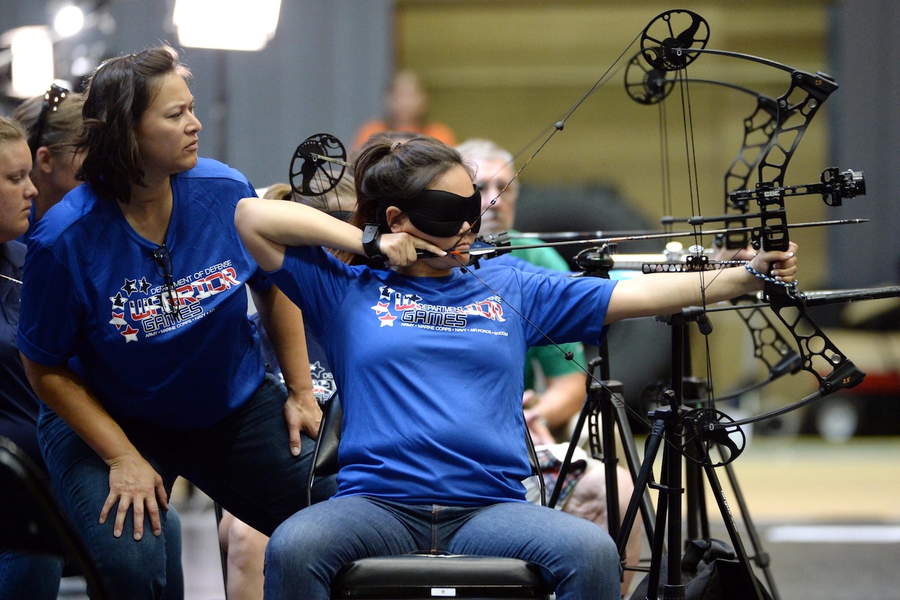 Air Force Master Sgt. Zarah Hartsock helps Air Force 1st Lt. Sarah M. Frankosky line up a shot during an archery competition for the visually impaired at the 2016 Department of Defense Warrior Games at the U.S. Military Academy in West Point, N.Y. June 17, 2016. Sound devices also help the archers aim at the targets. DoD photo by EJ Hersom