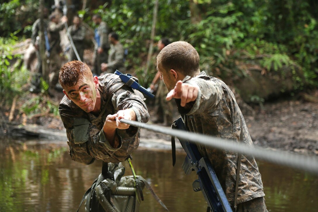 A U.S. soldier encourages a team member to reach the finish during the team obstacle course at the French jungle warfare school in Gabon, June 10, 2016. Army photo by Spc. Yvette Zabala-Garriga