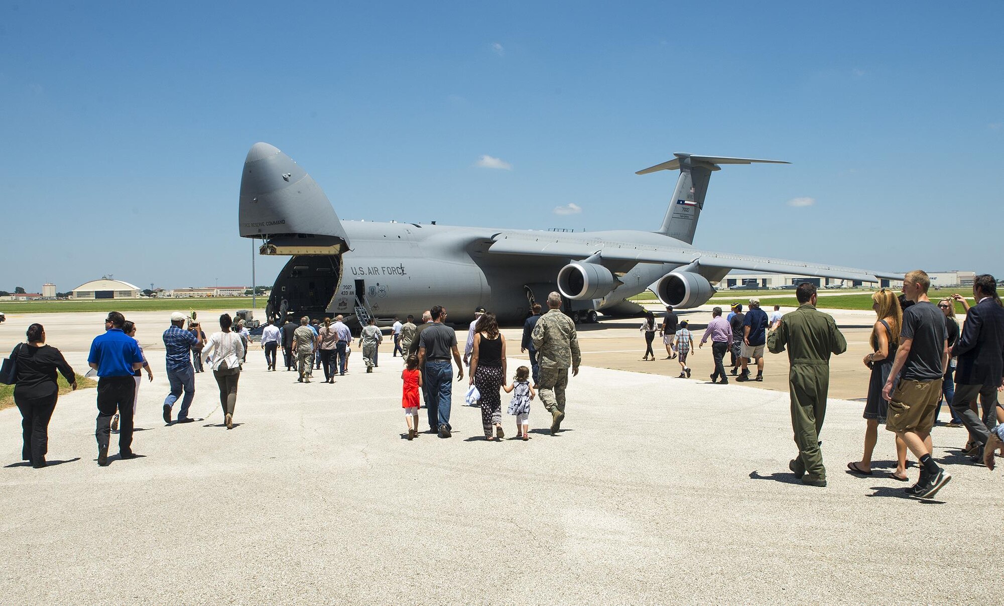 Family members and invited guests walk onto the flight line to tour the 433rd Airlift Wing's first C-5M Super Galaxy aircraft, bestowed "The City of San Antonio," June 17, 2016 after the transfer ceremony at Joint Base San Antonio-Lackland, Texas. The 433rd AW will receive nine C-5M models by late 2018, which is the result of a two-phase modernization effort that will improve fuel savings, climb rate, payload capability, and noise reduction.(U.S. Air Force photo by Benjamin Faske) 