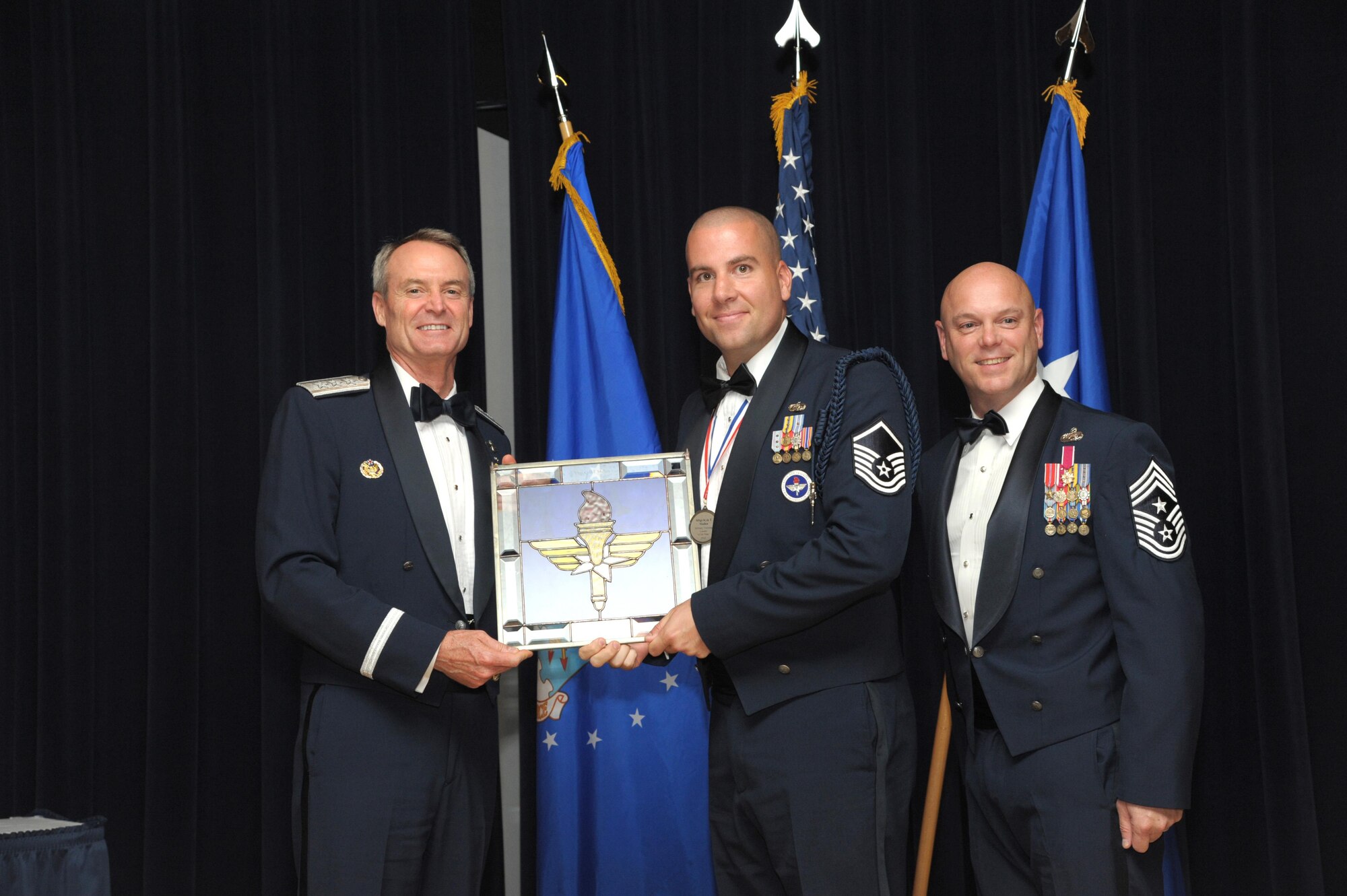 Tech. Sgt. Kyle Mullen, Technical Training Operations Center, Keesler Air Force Base, Mississippi, receives an award from Lt. Gen. Darryl Roberson, commander, Air Education and Training Command and AETC Command Chief Master Sgt. David Staton during a ceremony here, June 16. Mullen was selected as the AETC Military Training Leader of the Year. (U.S. Air Force photo by Joel Martinez)