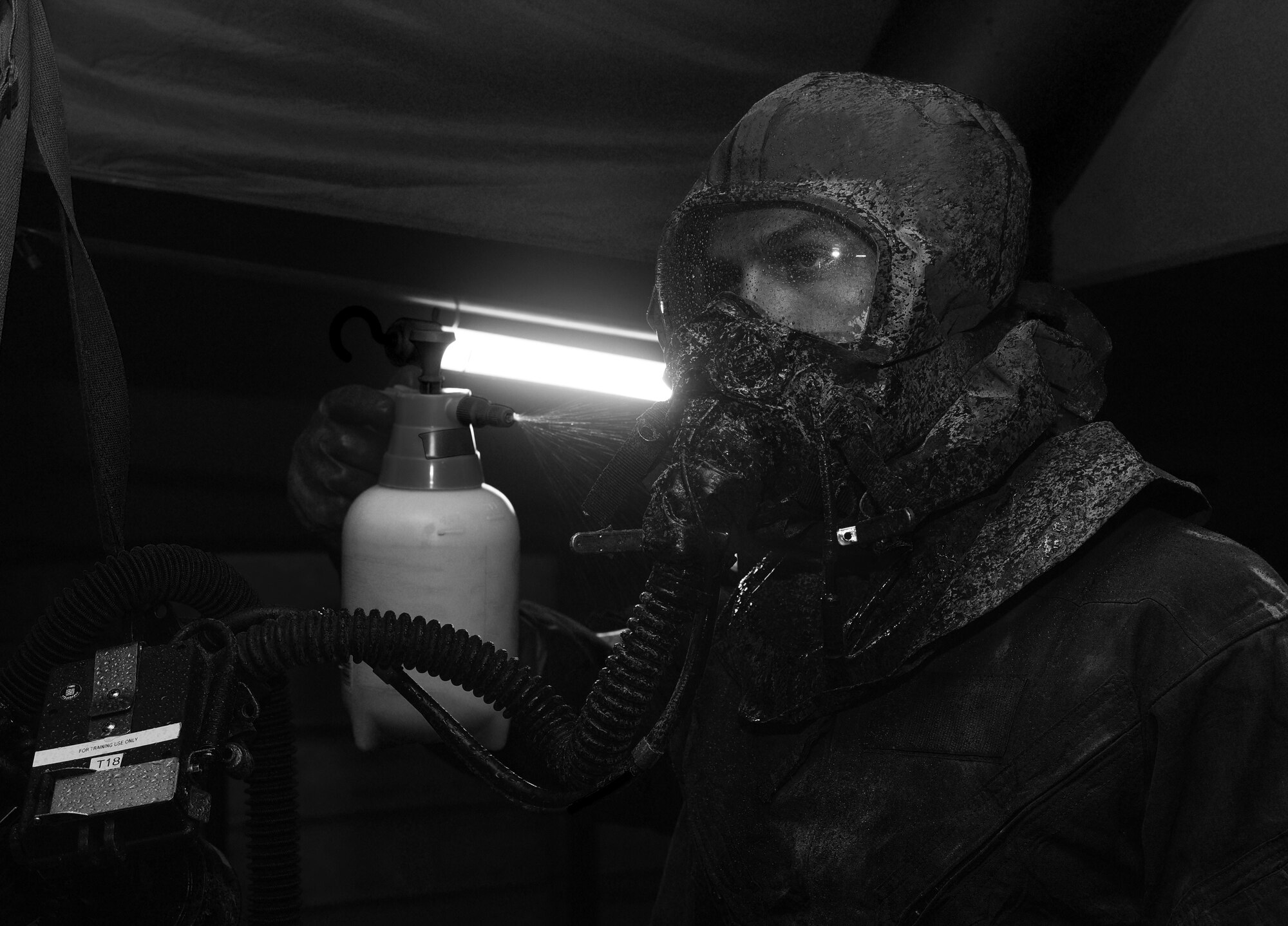 An aircrew flight equipment specialist sprays a simulated bleach solution on an aircrew member during the "final exam" phase of an Air Staff exerise rehearsing deployed decontamination processes. Air Force Special Operations Command’s operations directorate ran a realistic, scenario-based, training program for 16 Airmen from eight southern United States bases. (U.S. Air Force photo / Staff Sgt. Melanie Holochwost)