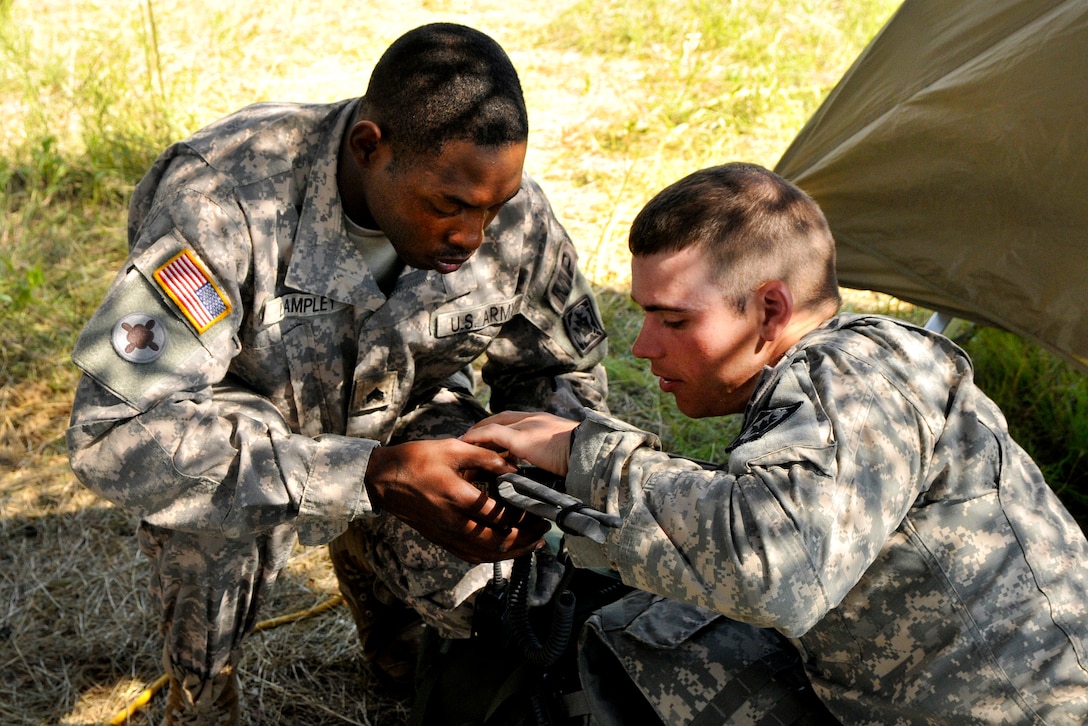 Army Spc. Eddie Lampley, left, and 2nd Lt. Anthony B. Hamilton troubleshoot a hand-held radio during a live-fire training exercise at Fort Hood, Texas, June 10, 2016. Lampley and Hamilton are assigned to the Mississippi Army National Guard’s 114th Military Police Company. Mississippi Army National Guard photo by Staff Sgt. Shane Hamann
