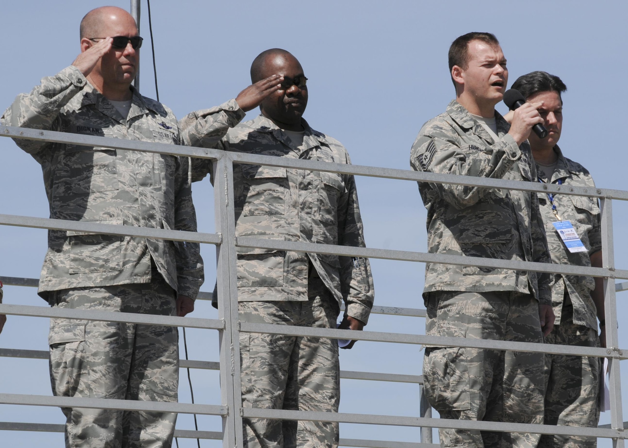 Col. James Dignan, 910th Airlift Wing commander, Lt. Col. Klavens Noel, 910th Airlift Wing chaplain, and Master Sgt. Bob Barko Jr., 910th Airlift Wing Public Affairs superintendent, salute as Tech. Sgt. Marshall Hunsaker, 910th Airlift Wing Public Affairs broadcast journalist, sings the National Anthem during the opening ceremony of the 2016 Youngstown Air Reserve Station Open House here, June 18. The open house drew approximately 7000 guests to see the equipment, mission and personnel of YARS. (U.S. Air Force photo/Tech. Sgt. Rick Lisum)