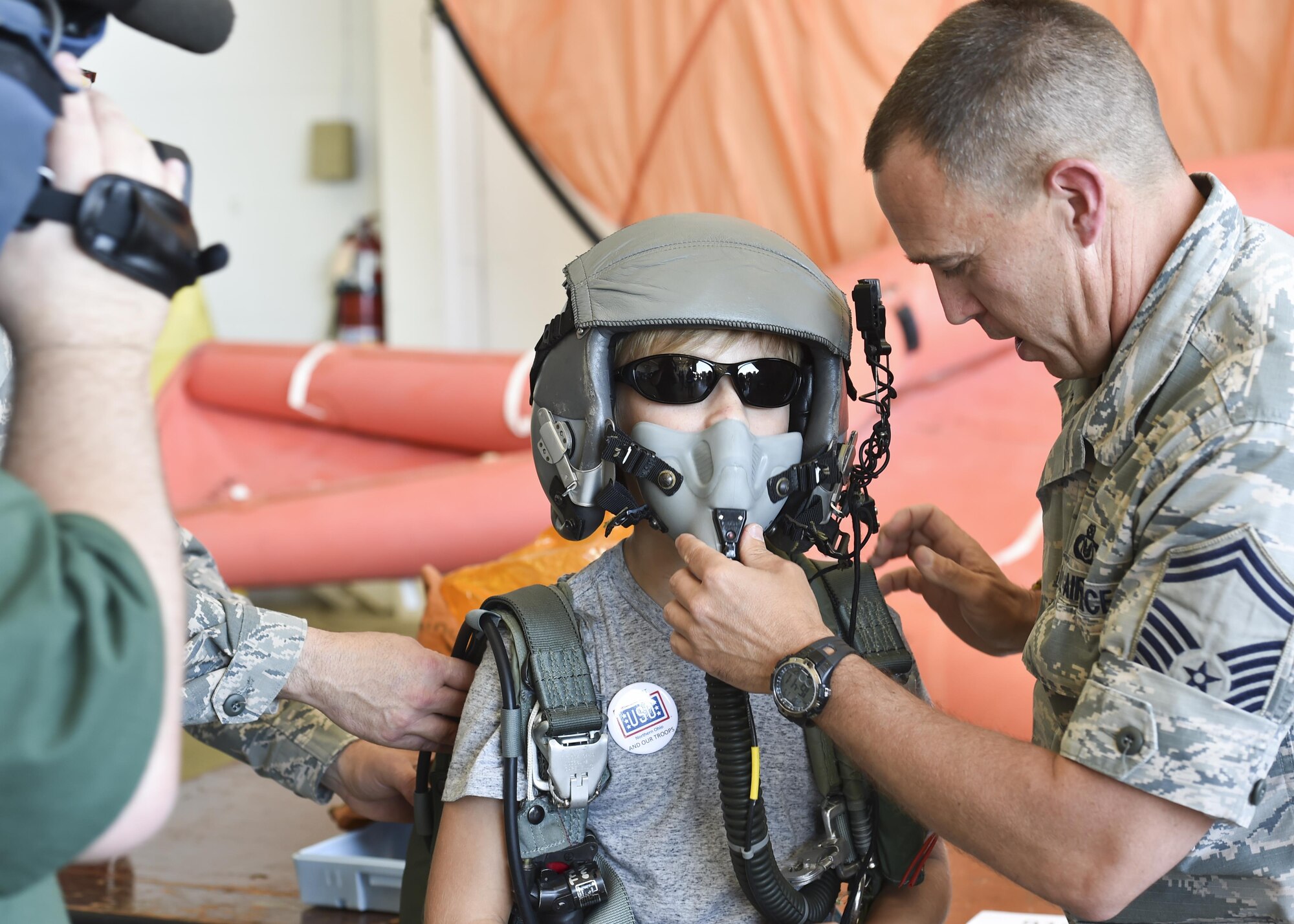 Senior Master Sgt. Jim Haupt, superintendent of the aircrew flight equipment shop with the 910th Operations Support Squadron here, helps 13-year-old open house guest Ethan Hoffman try on a flight helmet and parachute June 18, 2016. The AFE shop set up an interactive display as part of the 2016 Youngstown Air Reserve Station Open House which drew approximately 7000 guests to see the equipment, mission and personnel of YARS. (U.S. Air Force photo/Eric White)