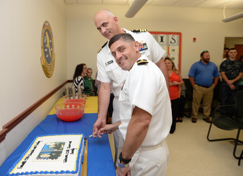 Lt. Cmdr. Kenneth Shaw III (front) assumes command of the Naval Branch Health Clinic-Albany in a change-of-charge ceremony at the Chapel of the Good Shepherd, aboard Marine Corps Logistics Base Albany, June 15. Shaw and the outgoing officer-in-charge, Cmdr. Raymond Bristol (rear), cut a cake during a celebratory reception held at NBHC-Albany in their honor after the event. Bristol had served at NBHC-Albany since June 2013. 
