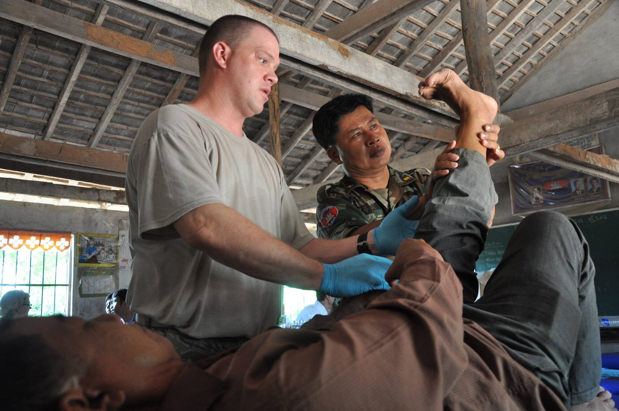 U.S. Air Force Tech. Sgt. Michael Lewis and Royal Cambodian Armed Forces Capt. Tob Vuthy treat a patient for lower back pain June 17, 2016, during Pacific Angel 16-2 in Kampot Province, Cambodia. Throughout the course of the week doctors, dentists, and pharmacists from the U.S., Cambodia, Australia, Vietnam and Thai militaries and two non-governmental organizations, along with 65 volunteers from the provincial hospital and local villages, saw more than 3,400 patients at two different sites. Together they provided general health, dental, optometry, pediatrics, and physical therapy services. (U.S. Air Force photo by Capt. Susan Harrington/Released)