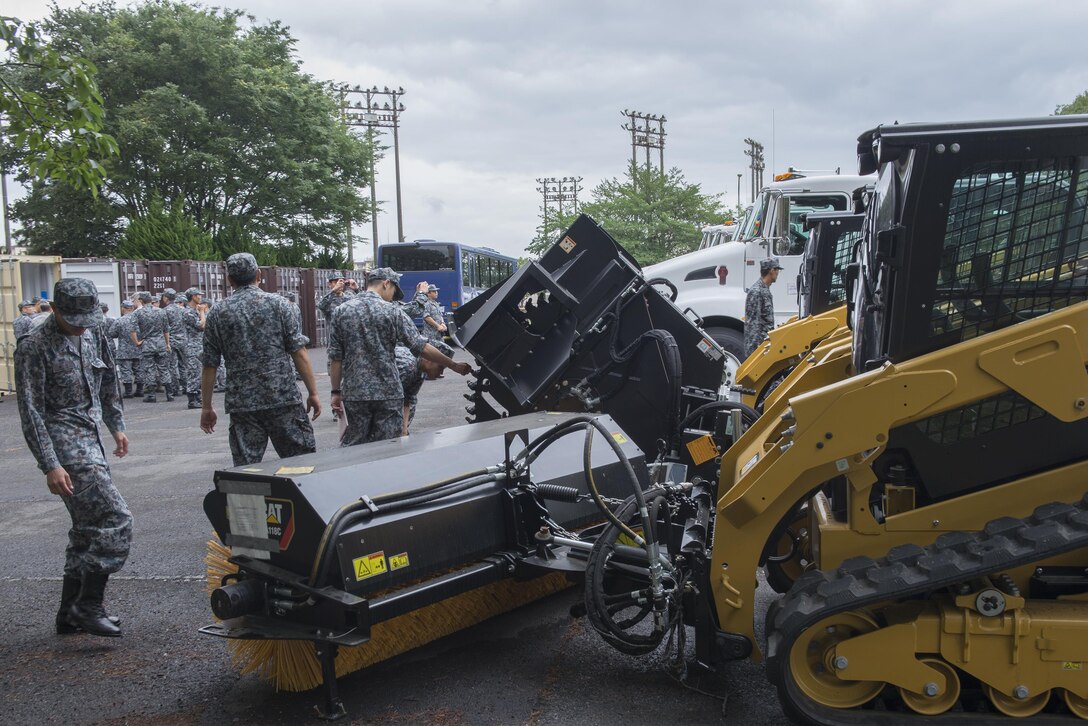 Japan Air Self-Defense Force members are shown skid-steer loaders with different attachments during a Prime Base Engineer Emergency Force tour at Yokota Air Base, Japan, June 16, 2016. The loader is a small, rigid-frame machine with lift arms used to attach a wide variety of labor-saving tools. (U.S. Air Force photo by Senior Airman David C. Danford/Released)