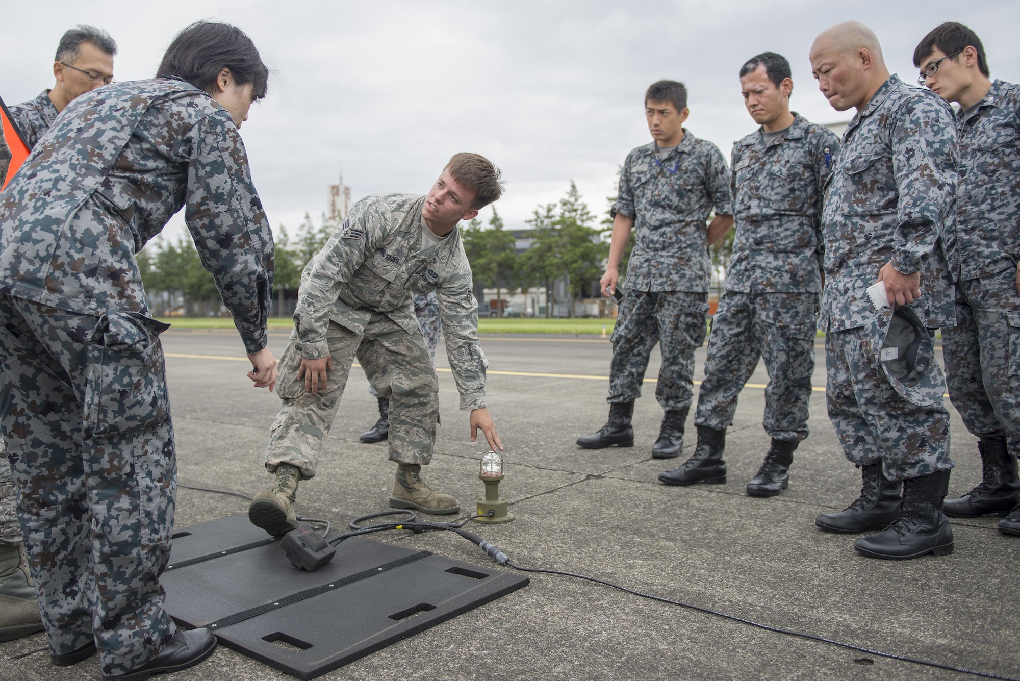 Senior Airman Scott Armstrong, 374th Civil Engineer Squadron electrical systems technician, highlights the emergency airfield lighting system at Yokota Air Base, Japan, June 16, 2016. If, for any reason, the runway lights do not-function, the 374 CES deploys a portable system to fill in until the lights are fixed, ensuring the safety of pilots and aircrew. (U.S. Air Force photo by Senior Airman David C. Danford/Released)