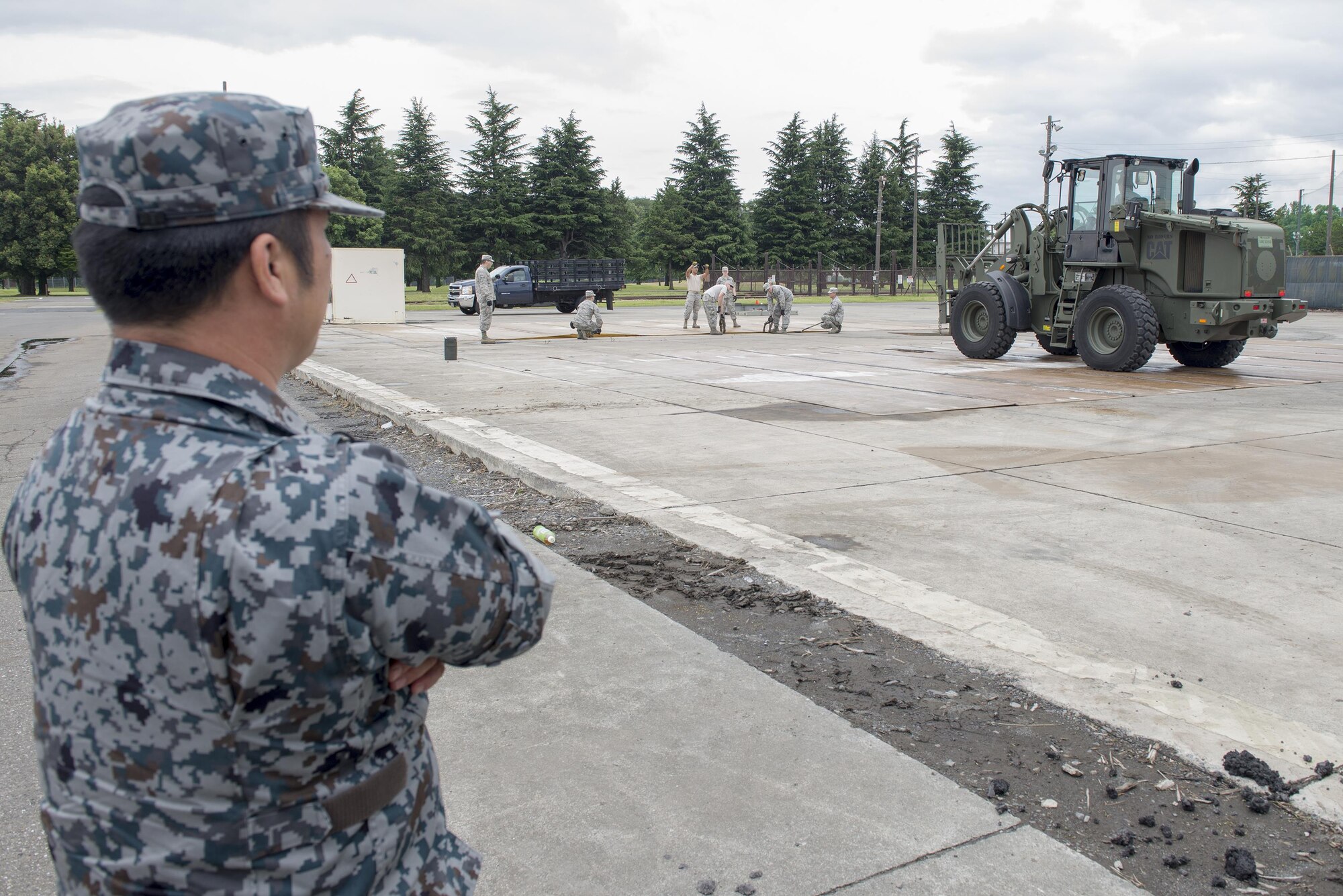 Airmen assigned to the 374th Civil Engineer Squadron deploy folded fiberglass mats as part of a demonstration at Yokota Air Base, Japan, June 16, 2016. The mats are used to cover recently filled craters to prevent foreign object debris during airfield damage repair. (U.S. Air Force photo by Senior Airman David C. Danford/Released)