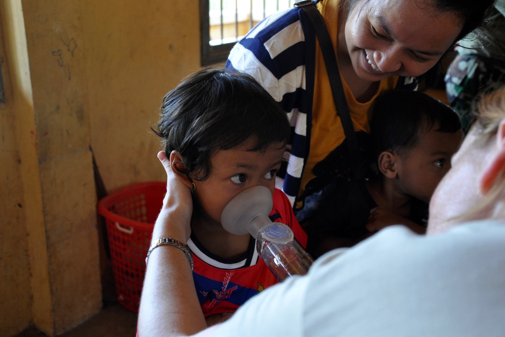 U.S. Air Force Capt. Tasha Hellu, a pediatric physician deployed from the 36th Medical Group, Anderson Air Force Base, Guam, teaches a young Cambodian girl to breath in medicine to treat asthma June 13, 2016, during Pacific Angel 16-2 in Kampot Province, Cambodia. The health services outreach team set up a mobile clinic at two different sites throughout the week, Por Thivong Primary School in Tuek Chhou district June 13-15, and at the Ang Chum Trapaing Chhuk Secondary School in Kampong Trach district June 16-18. The clinics included general health, optometry, dental, family medicine and physical therapy services, as well as a small pharmacy. (U.S. Air Force photo by Capt. Susan Harrington/Released)