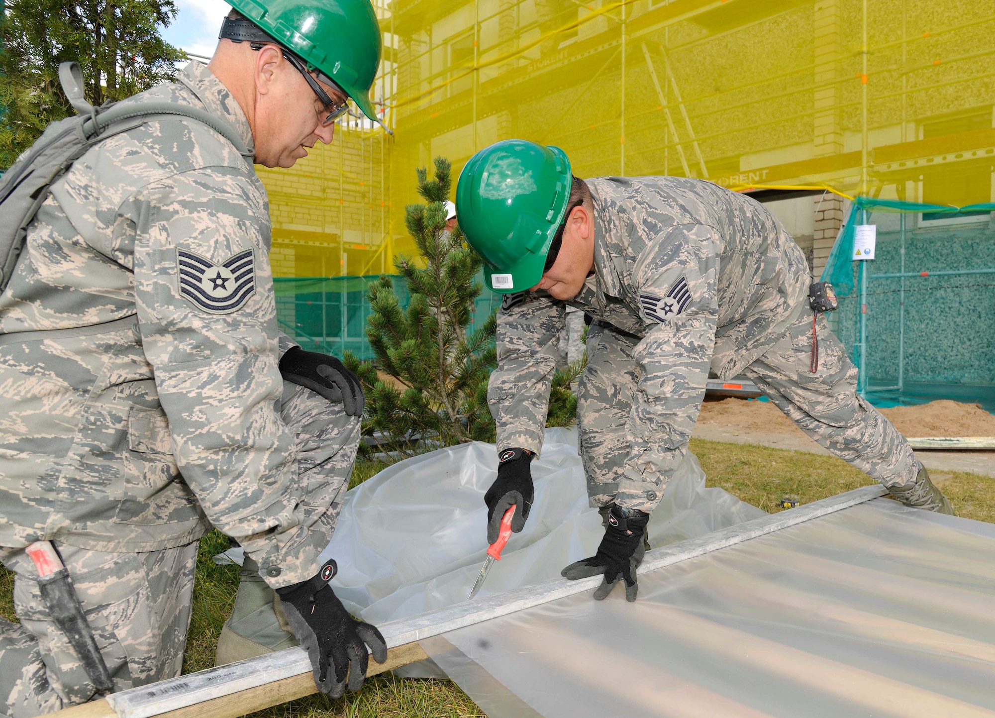 Tech. Sgt. Ken Wilson, 127th Civil Engineering Squadron HVAC supervisor and Staff Sgt. Jared Brunsen, 127th CES HVAC expert, cut sheet plastic at a kindergarten in Silmala, Latvia on June 18, 2016. The school’s renovations are part of a Humanitarian-Civic Assistance project. The project provides training opportunities for the United States and Latvian soldiers as well as a benefit for the local community. (U.S. Air National Guard photo by Senior Airman Ryan Zeski)
