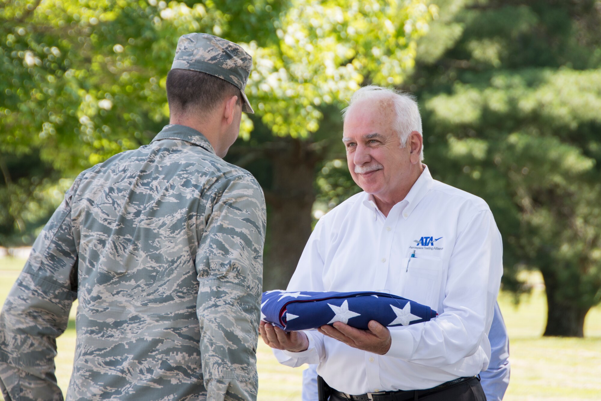 Steve Pearson (right), former Aerospace Testing Alliance general manager, accepts a U.S. flag from 1st Lt. Christopher Handy after a flag ceremony June 17 at Arnold Engineering Development Complex in honor of Pearson’s service to the Arnold Air Force Base AEDC. Pearson accepted a position with Jacobs Aerospace and Technology and his last day of service to ATA was June 17. (U.S. Air Force photo/Jacqueline Cowan)