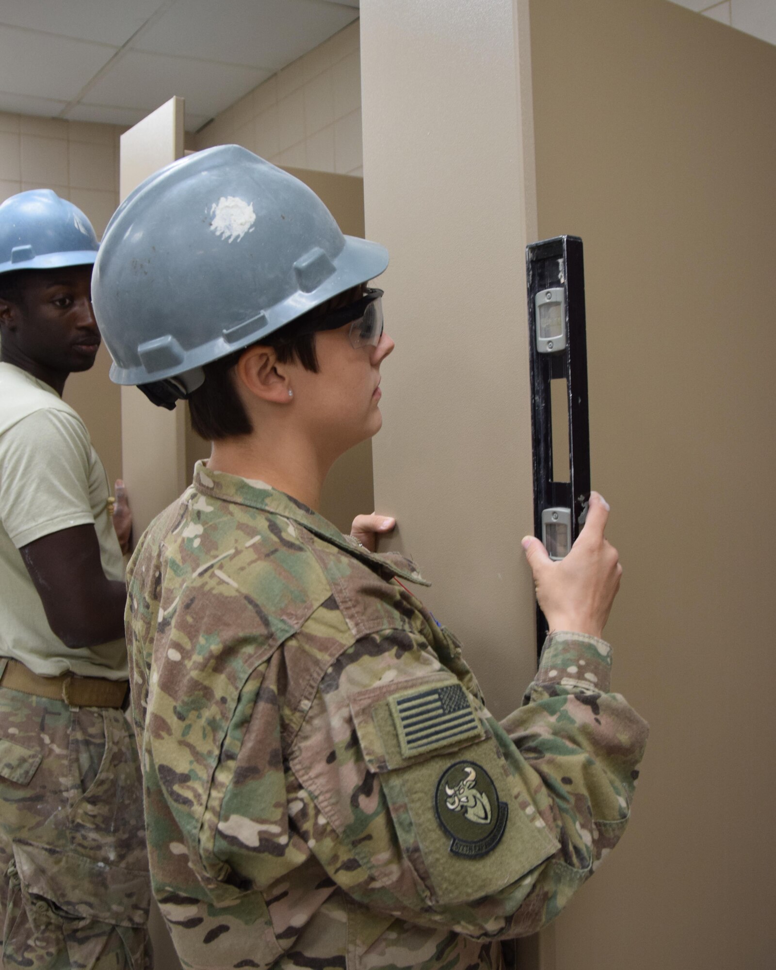 Senior Airman Keonte Lewis watches as Senior Airman Candice Edwards, water and fuels systems maintenenace journeyman from the 577th Expeditionary Prime Beef Squadron out of the 1st Expeditionary Civil Engineer Group, checks a level to insure a shower partition balanced as part of the cadillac renovation at the Coalition Compound June 14, 2016 at Al Udeid Air Base, Qatar. A variety f Air Force Specialty Codes from the Civil Engineering career field worked 12  hour shifts daily for the past three months to complete the project.(U.S. Air Force photo/Technical Sgt. Carlos J. Trevino/Released)