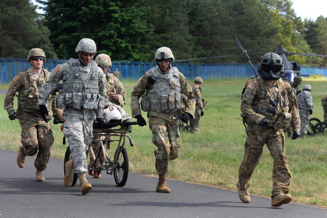 An Army crew chief, right, escorts a stretcher team delivering a simulated patient to a makeshift emergency room during a mass casualty exercise as part of Anakonda 2016 in Miloslawiec, Poland, June 11, 2016. Army photo by Sgt. 1st Class John Fries