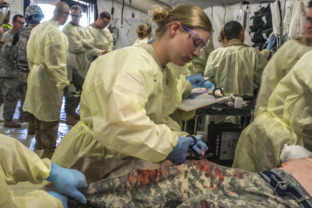 A soldier cuts the trousers away from a simulated patient, enabling her to further examine the patient's injuries during a mass casualty exercise as part of Anakonda 2016 in Miloslawiec, Poland, June 11, 2016. Army photo by Sgt. 1st Class John Fries