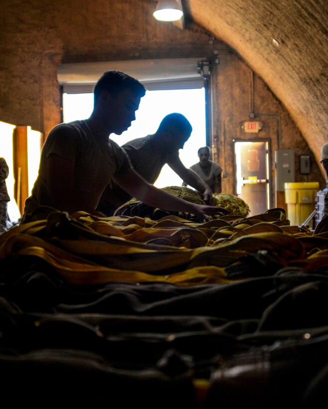 379th Expeditionary Operations Support Squadron aircrew flight equipment journeymen accordion-fold a drag parachute prior to packing it into the case assembly, which is then installed onto a B-52 Stratofortress June 15, 2016, at Al Udeid Air Base, Qatar. Each of the 16 drag chutes here are allowed to deploy 160 times. Inspecting the 180-pound drag chute prior to repacking is vital because the smallest knot can make the difference between a successful chute deployment and disaster. (U.S. Air Force photo/Senior Airman Janelle Patiño/Released)