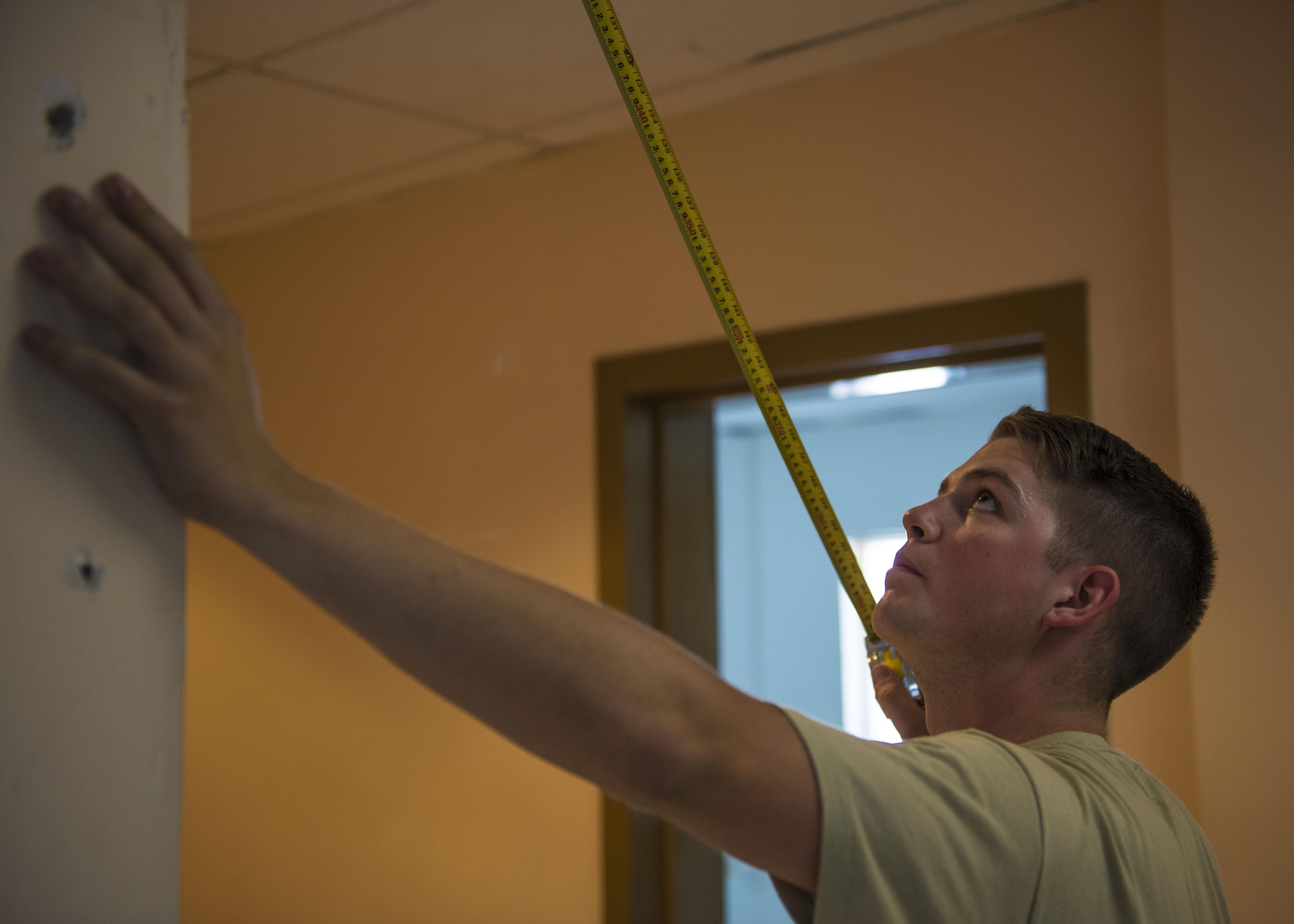 Senior Airman Jonathan Brooks, 455th Expeditionary Civil Engineer Squadron structural journeyman, gets measurements to construct a wall in the 455th Air Expeditionary Wing Headquarters building, June 20, 2016, Bagram Airfield, Afghanistan. Members of the 455th ECES structures flight construct and repair buildings and other military structures from the foundation up. (U.S. Air Force photo by Senior Airman Justyn M. Freeman)