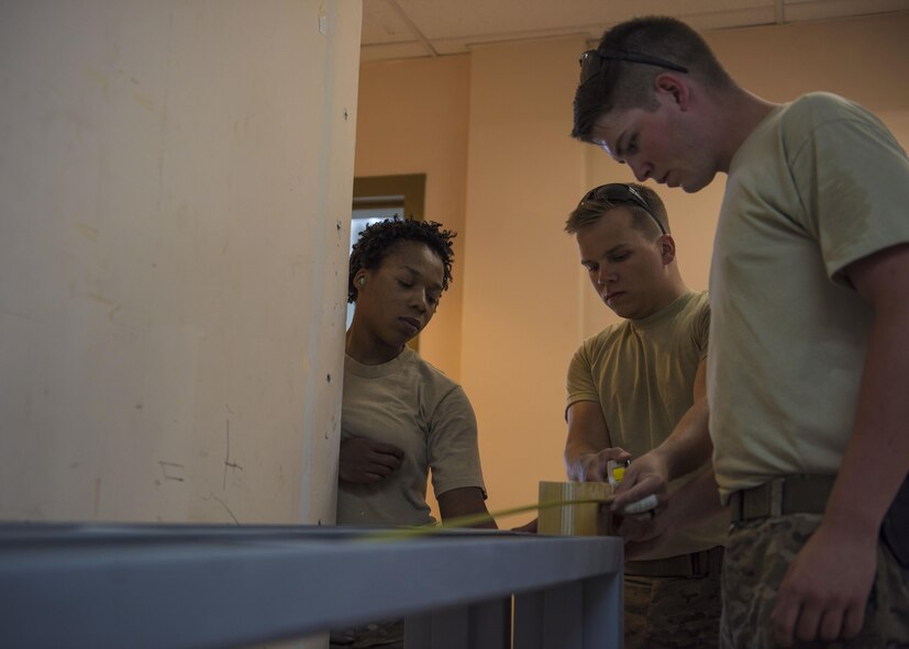 Senior Airman Jonathan Brooks (right), Senior Airman Eric Woolston (center), and Airman 1st Class Taylor Davis (left), 455th Expeditionary Civil Engineer Squadron structural journeyman, take measurements of a door frame while constructing a wall in the 455th Air Expeditionary Wing Headquarters building, June 20, 2016, Bagram Airfield, Afghanistan. Members of the structures flight are building the wall as part of an ongoing renovation project. (U.S. Air Force photo by Senior Airman Justyn M. Freeman)