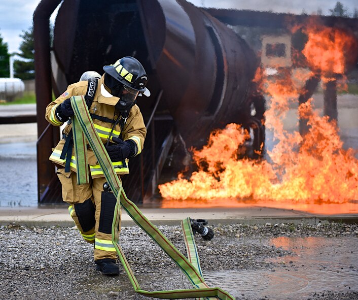 As flames continue to dance around the aircraft simulator, a  firefighter with the 932nd Airlift Wing pulls back hose in preparation for another training evolution, May 14, 2016, Scott Air Force Base, Illinois.  The fire pit and aircraft fire simulator allow for firefighters to train with real flames and possible aircraft emergency situations. (U.S. Air Force photo by Tech. Sgt. Christopher Parr)