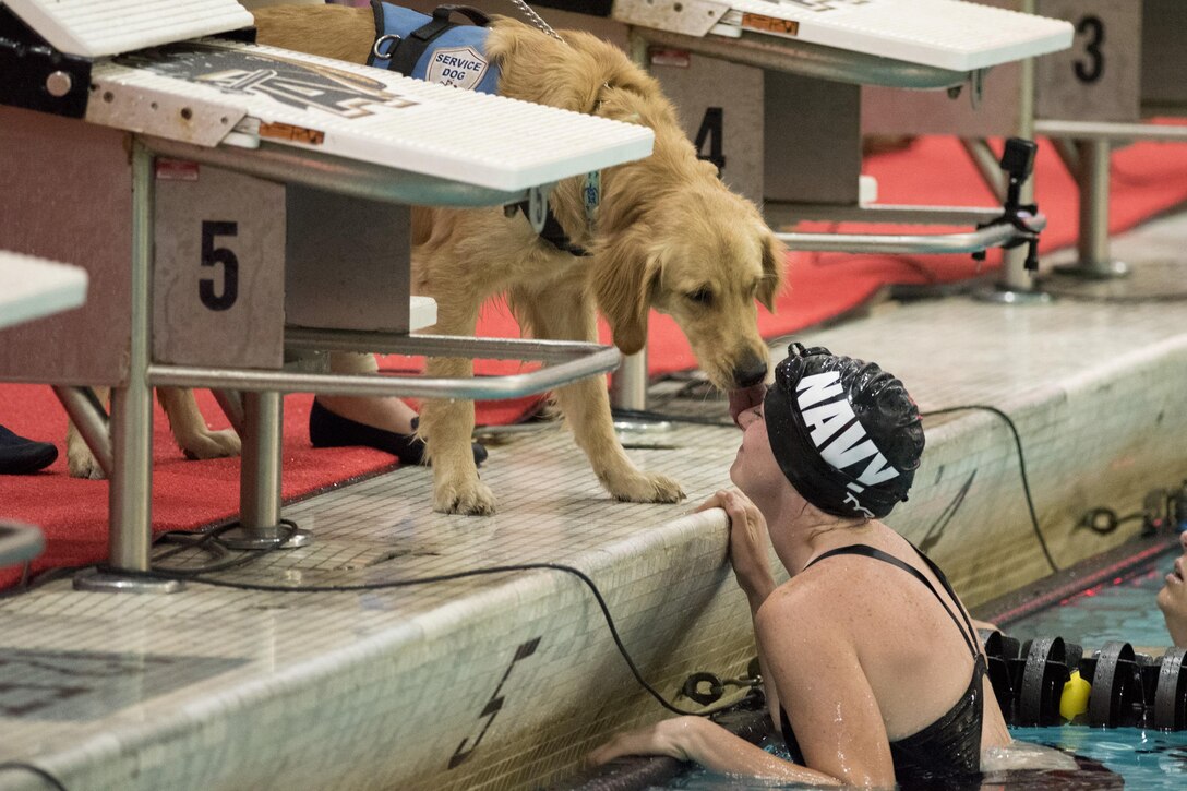 Navy Petty Officer 3rd Class Abbie Johnson gets a kiss from Kona, her military service dog, after competing in a swimming during the 2016 Department of Defense Warrior Games at the U.S. Military Academy in West Point, N.Y., June 20, 2016. DoD photo by Roger Wollenberg