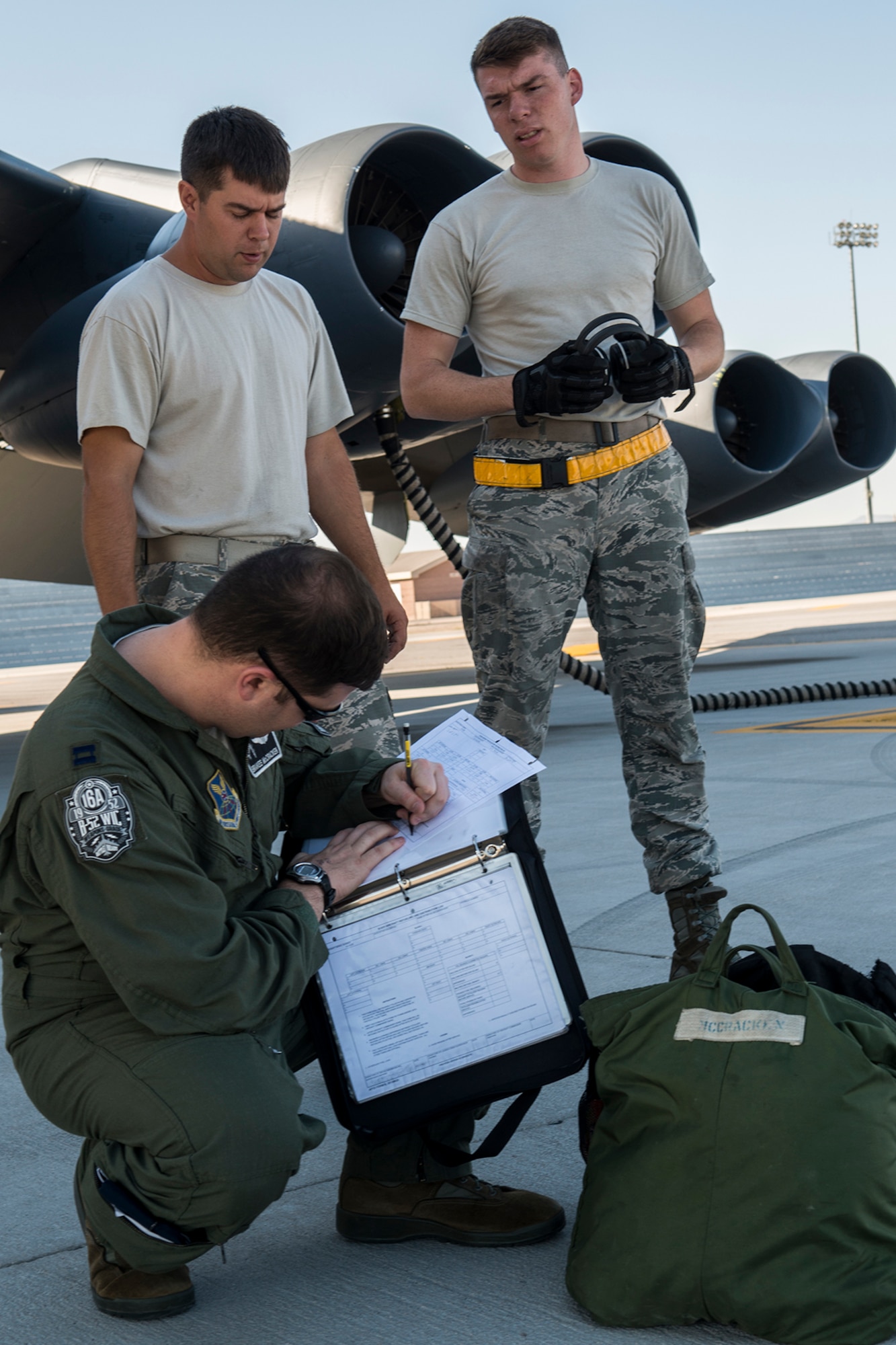 U.S. Air Force B-52H Stratofortress crew chiefs Staff Sgt. Patrick Deslauriers (left), 307th Aircraft Maintenance Squadron, and Airman First Class Jacob Lieuallen, 11th Aircraft Maintenance Unit, wait as an aircrew member looks over the aircraft forms before a mission on June 8, 2016, Nellis Air Force Base, Nev. The Airmen are among 45 maintenance personnel on temporary duty at Nellis in support of the 340th Weapons Squadron. (U.S. Air Force photo by Master Sgt. Greg Steele/Released)