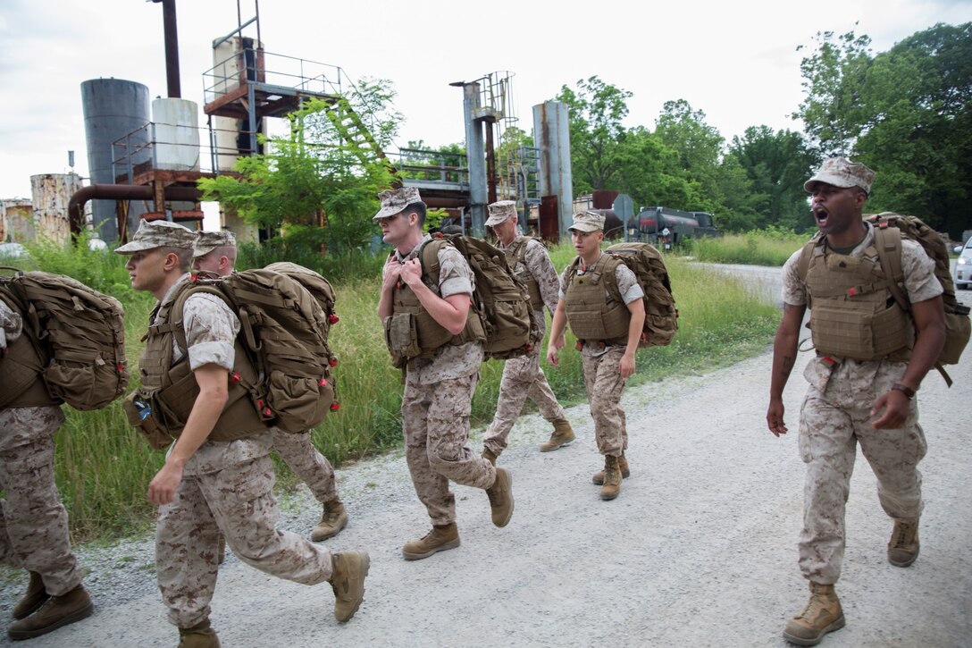 Sgt. Azed K. Exime (right), satellite communications operator with Support Company, 6th Communications Battalion, Force Headquarters Group, Marine Forces Reserve, calls out cadence to the Marines on a hike through the trails at the Muscatatuck Urban Training Center in Butlerville, Ind., June 10, 2016. The Marines battled hills and weather conditions during the hike and pushed each other to finish strongly. (U.S. Marine Corps photo by Lance Cpl. Melissa Martens/ Released)