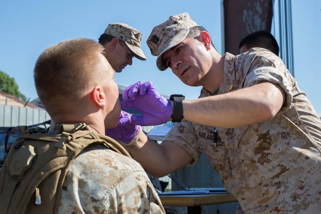 Navy Lt. Wilson Aguilargarcia (right), general dentist with 14th Dental Company, 4th Dental Battalion, Marine Forces Reserve, provided Marines with dental exams at the Muscatatuck Urban Training Center in Butlerville, Ind., June 11, 2016. The dental crew brought their equipment out to the field so Marines did not have to be taken out of the training environment for their annual exams and x-rays. (U.S. Marine Corps photo by Lance Cpl. Melissa Martens/ Released) 