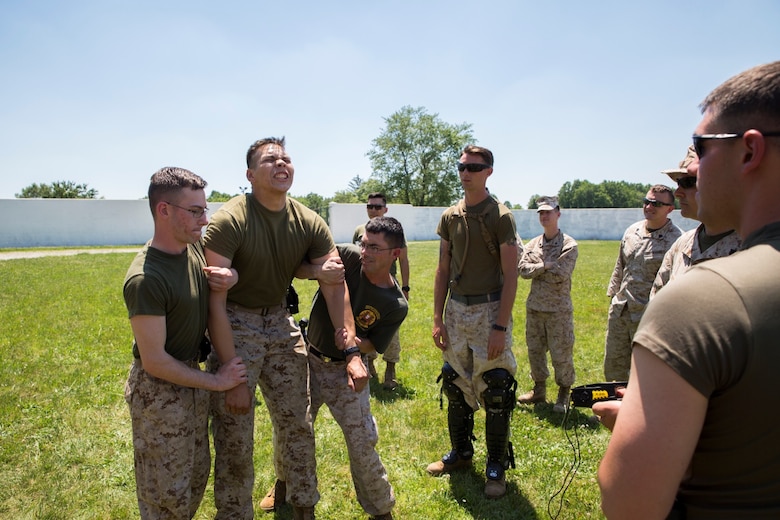 Lance Cpl. Johnny T. Banuelos (second from left), a military policeman with 4th Law Enforcement Battalion, Force Headquarters Group, Marine Forces Reserve, is guided to ground after being tased during non-lethal weapons training at the Muscatatuck Urban Training Center in Butlerville, Ind., June 11, 2016. It is important for Marines to understand how to effectively operate gear they carry and how it will affect the body once administered.  (U.S. Marine Corps photo by Lance Cpl. Melissa Martens/ Released) 