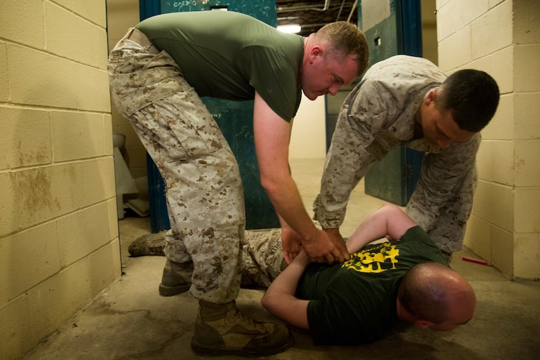 Marines with 4th Law Enforcement Battalion, Force Headquarters Group, Marine Forces Reserve, restrain an inmate during detainee operations training at the Muscatatuck Urban Training Center in Butlerville, Ind., June 14, 2016. The Marines conducted drills on different scenarios and learned how to run and sustain a prison safely and effectively. (U.S. Marine Corps photo by Lance Cpl. Melissa Martens/ Released)