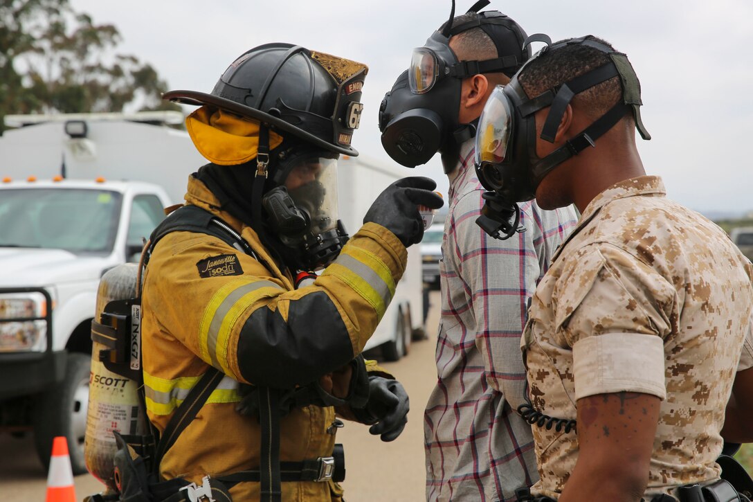 A firefighter with the Marine Corps Air Station Miramar Fire Department decontaminates a suspect and a military police officer with the Provost Marshal’s Office during a Chemical, Biological, Radiological, Nuclear and High-Yield Explosives (CBRNE) exercise at the gas chamber aboard Marine Corps Air Station Miramar, Calif., May 18. The exercise revolved around PMO, the Miramar Fire Department, Explosive Ordnance Disposal, and Aircraft Rescue and Firefighting working together to identify and eliminate the threat of a simulated clandestine drug lab. (U.S. Marine Corps photo by Cpl. Alissa Schuning/Released)